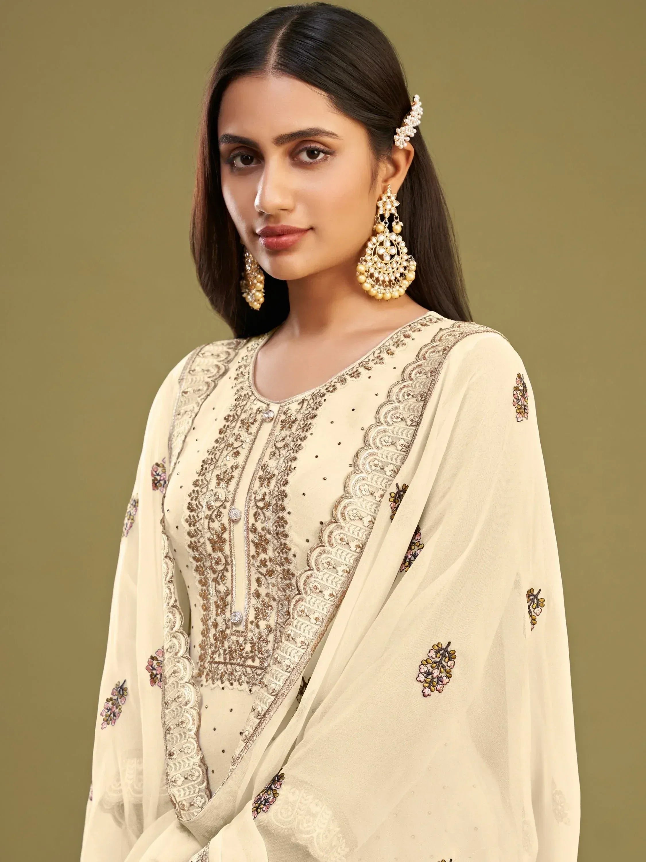 Elegant cream salwar kameez with floral embroidery and gold detailing, paired with statement earrings.