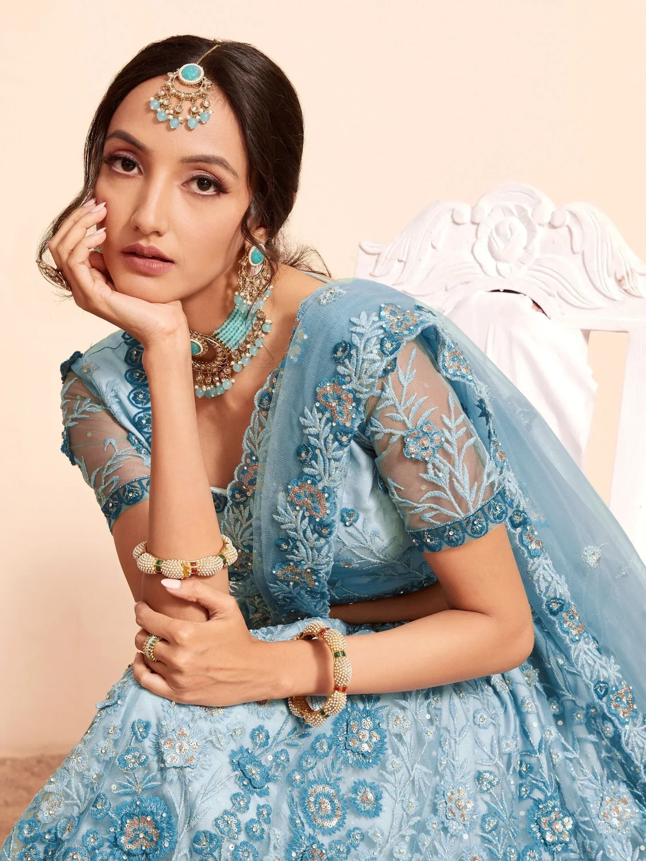 Blue embroidered lehenga choli with floral detailing, matching jewelry, and sheer dupatta for Indian ethnic wear