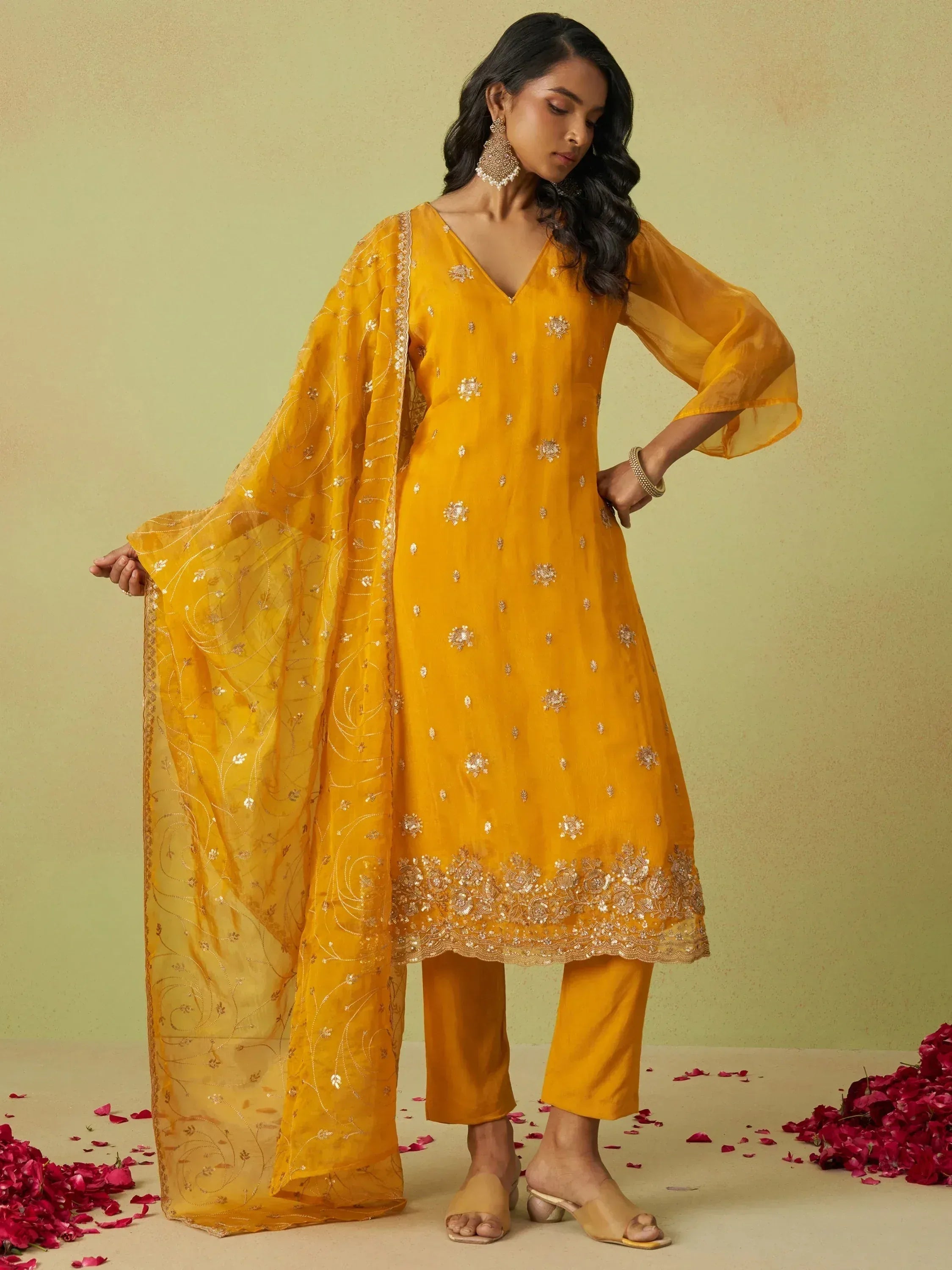 Yellow embroidered salwar kameez with matching dupatta, floral embellishments, and rose petals