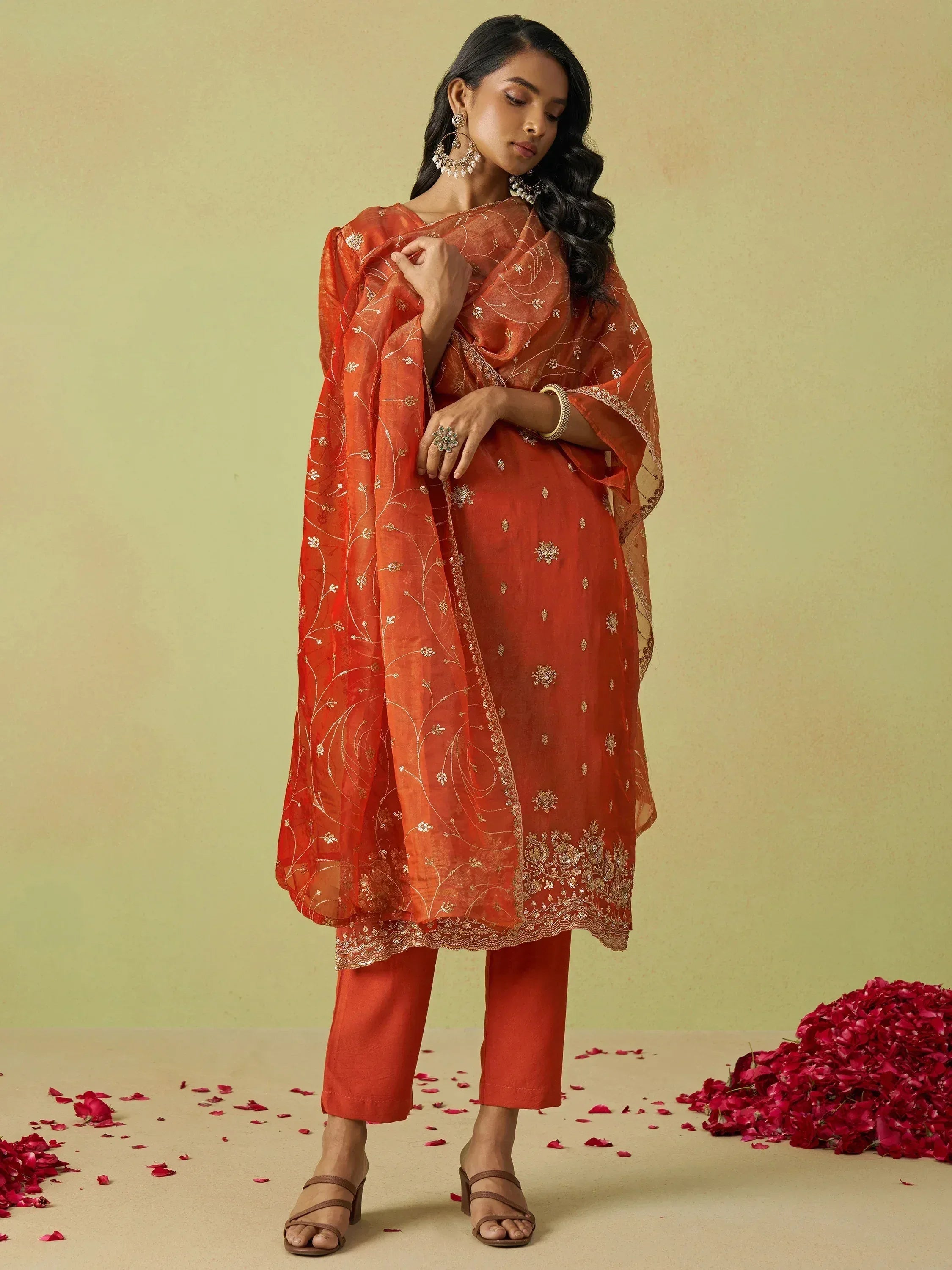 Orange embroidered salwar kameez with dupatta, floral detailing, and rose petals