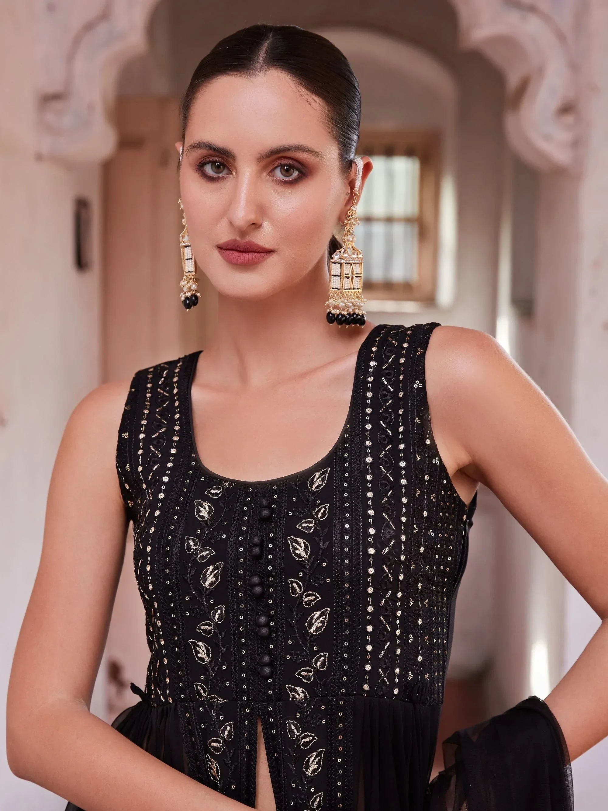 Woman wearing black embroidered ethnic gown with gold earrings, modern Indian fashion