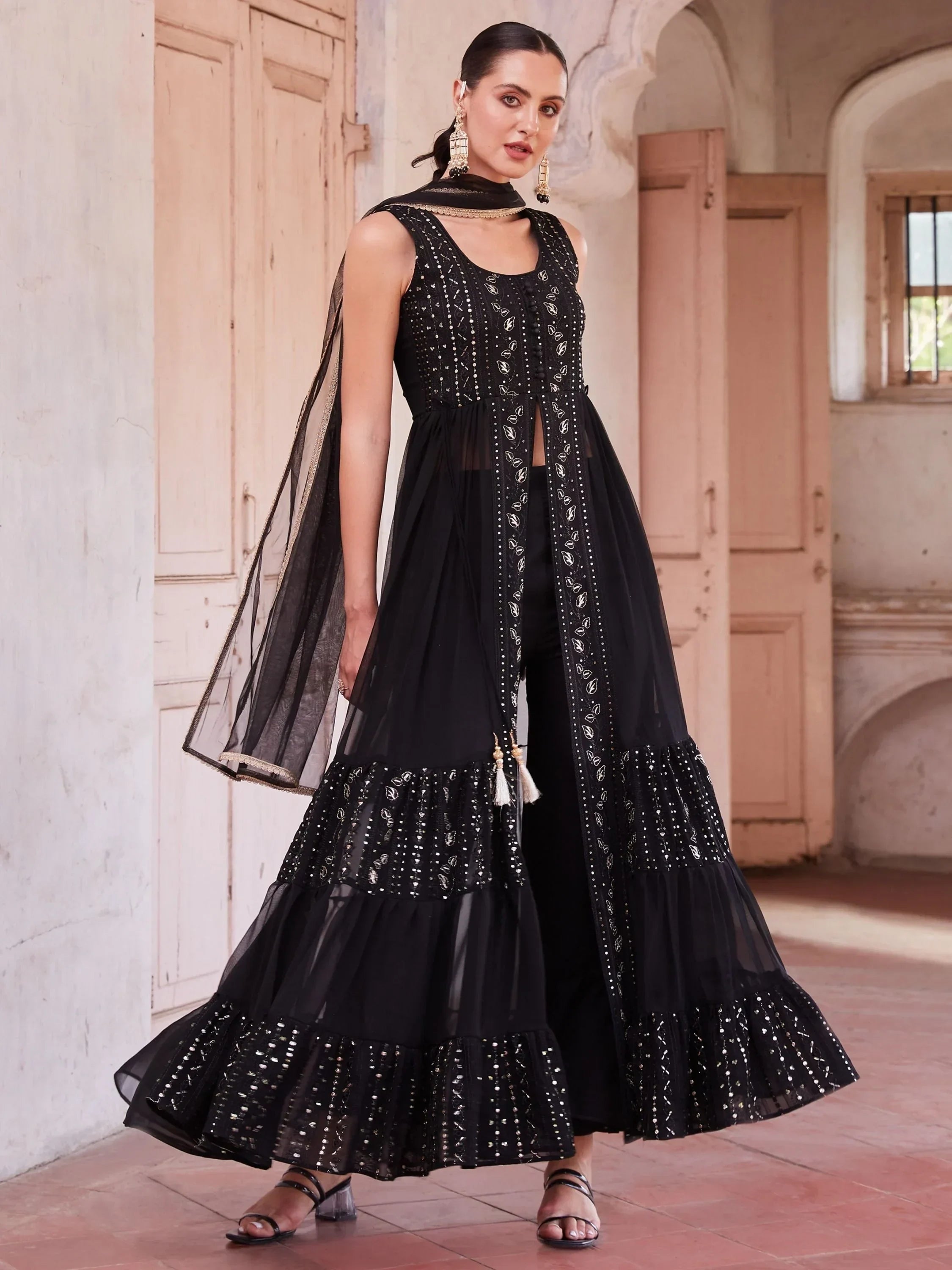 Woman wearing a black embroidered ethnic gown with dupatta in a traditional setting