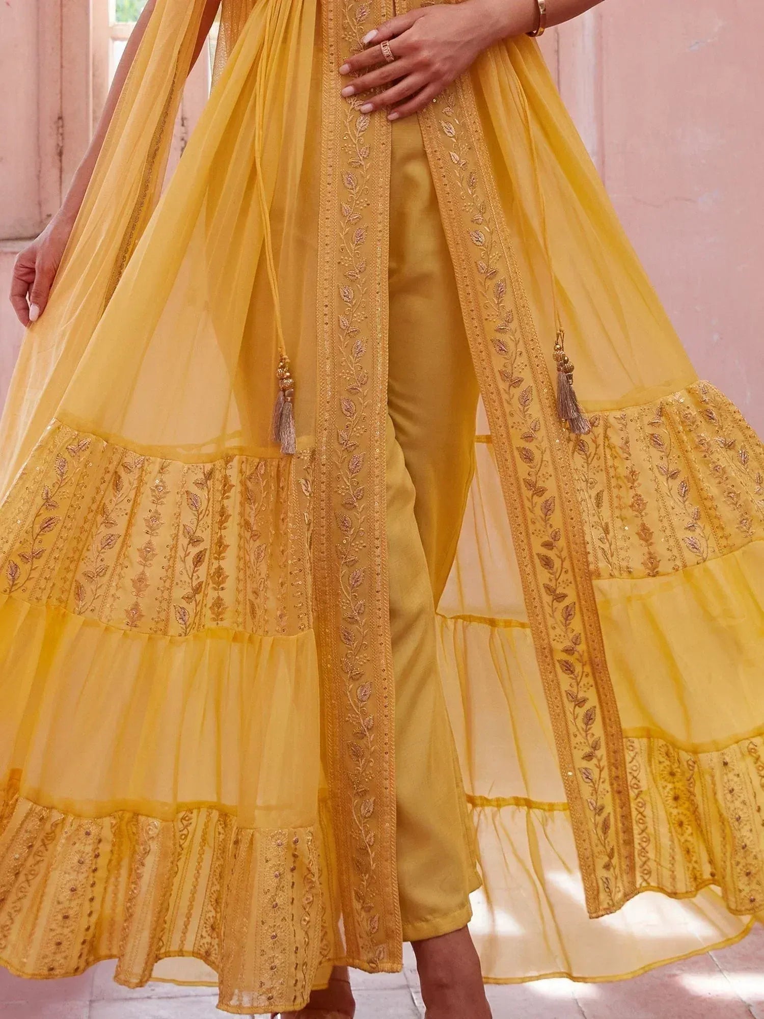 Yellow embroidered ethnic sharara suit with layered dupatta and tassels, perfect for Indian occasions