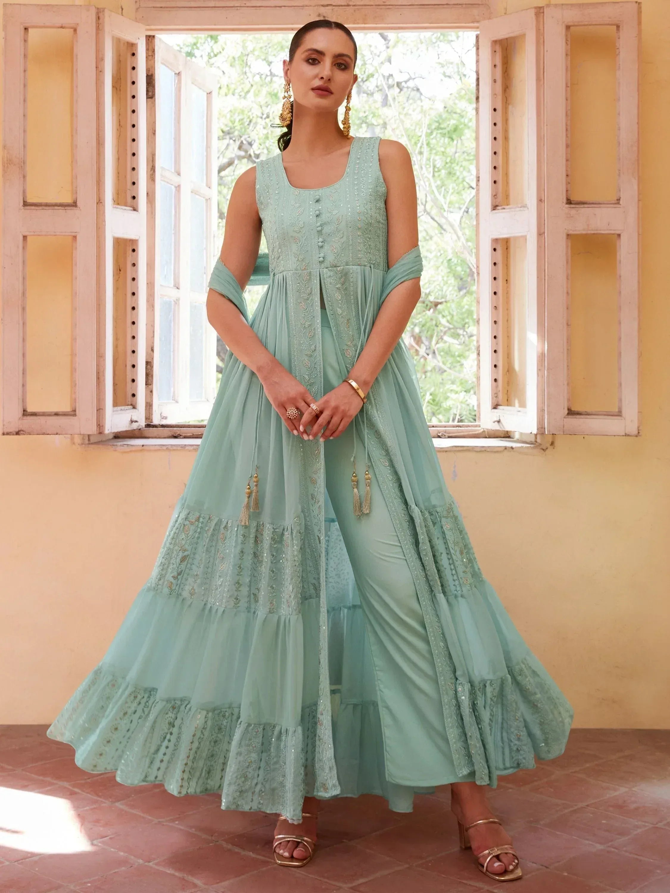 Mint green embroidered ethnic gown with layered skirt and cold shoulder sleeves, perfect for Indian occasions.