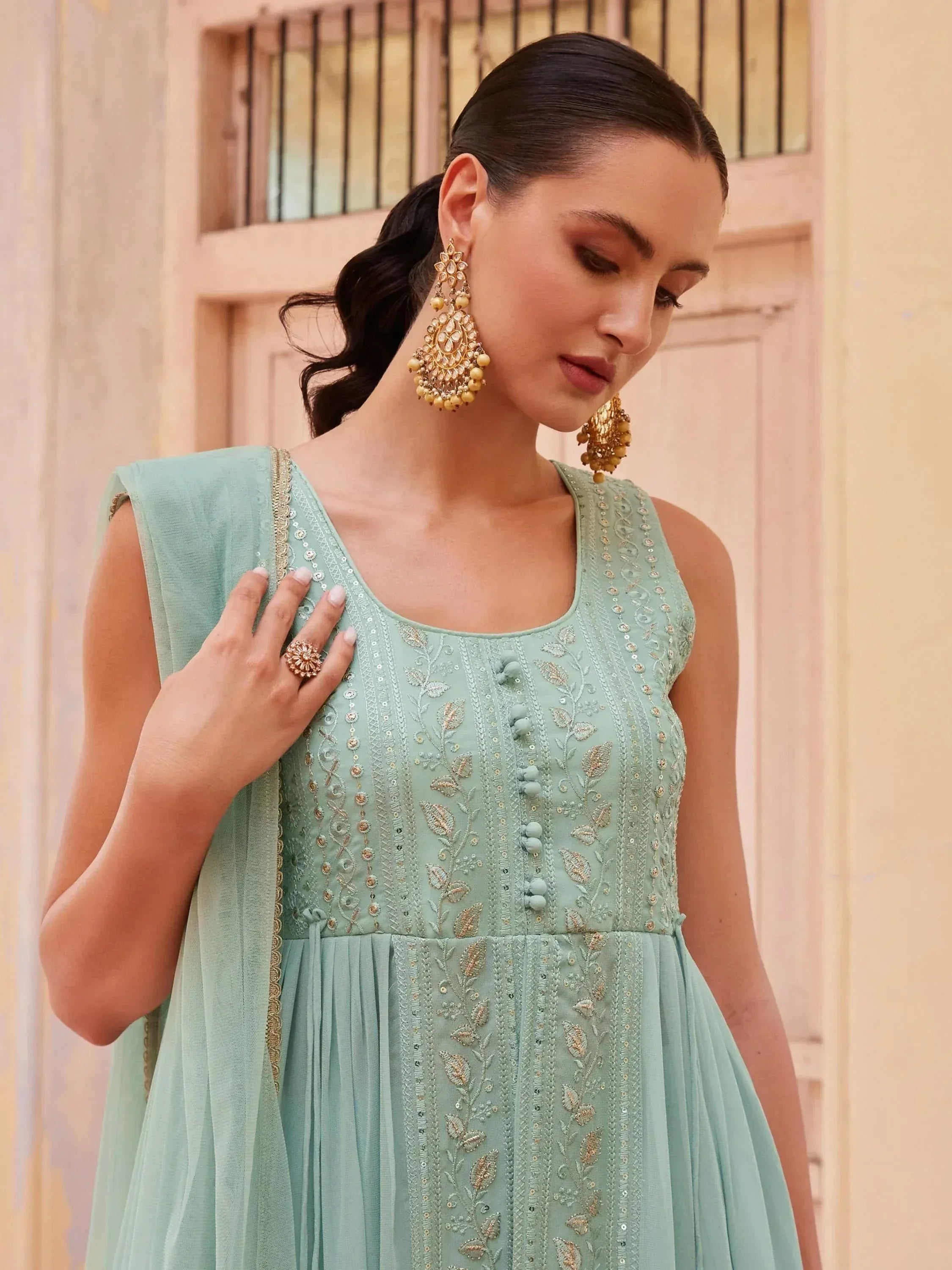 Mint green embroidered ethnic gown with gold detailing and matching dupatta, styled with jhumka earrings