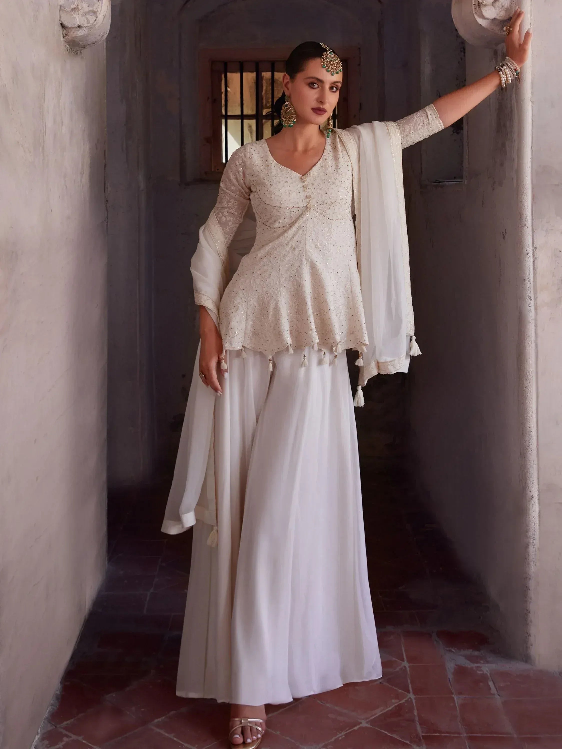 Woman in elegant off-white ethnic palazzo suit with dupatta and traditional jewelry
