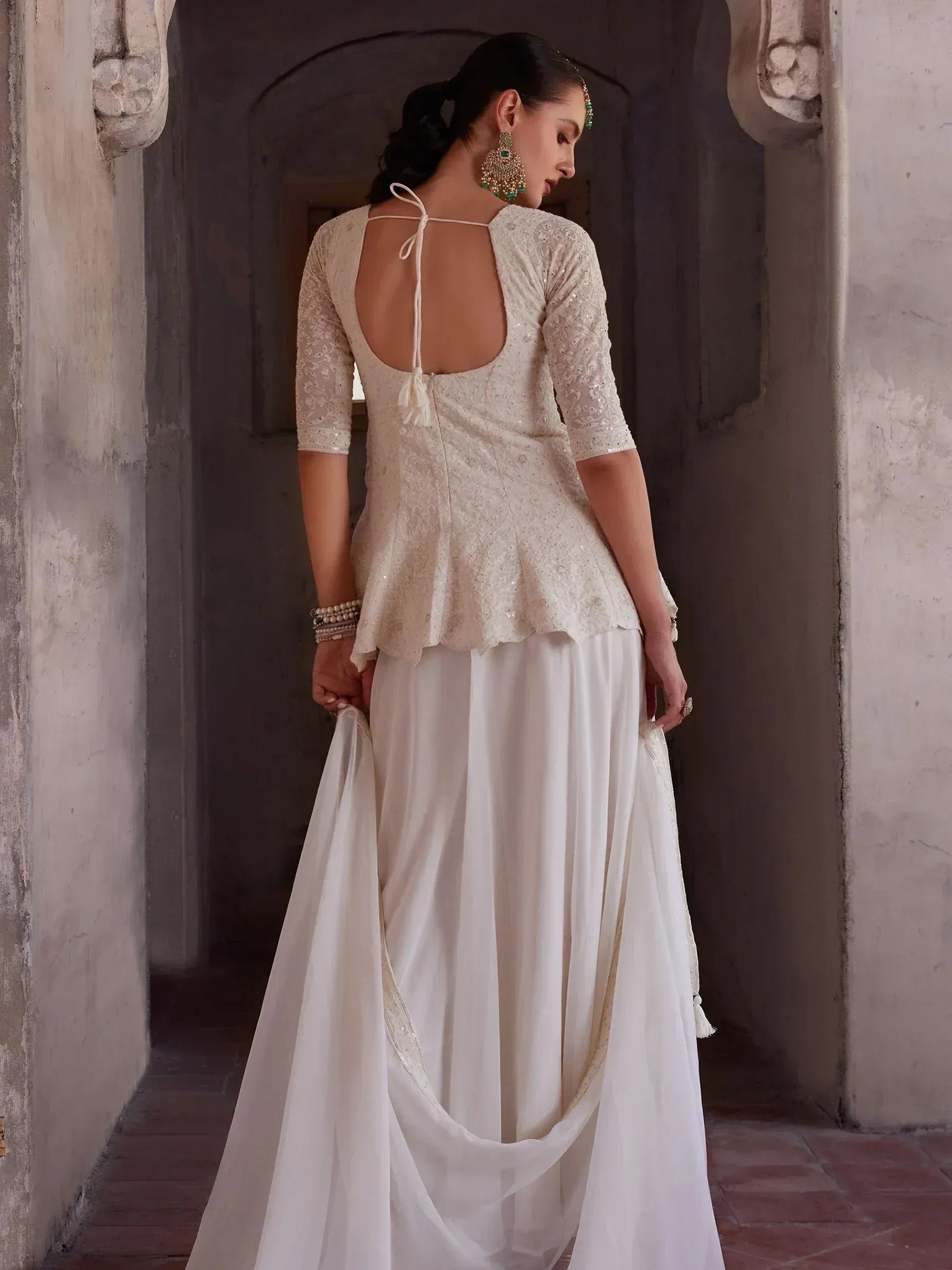 Woman in elegant ivory lehenga choli with open back blouse and traditional jewelry