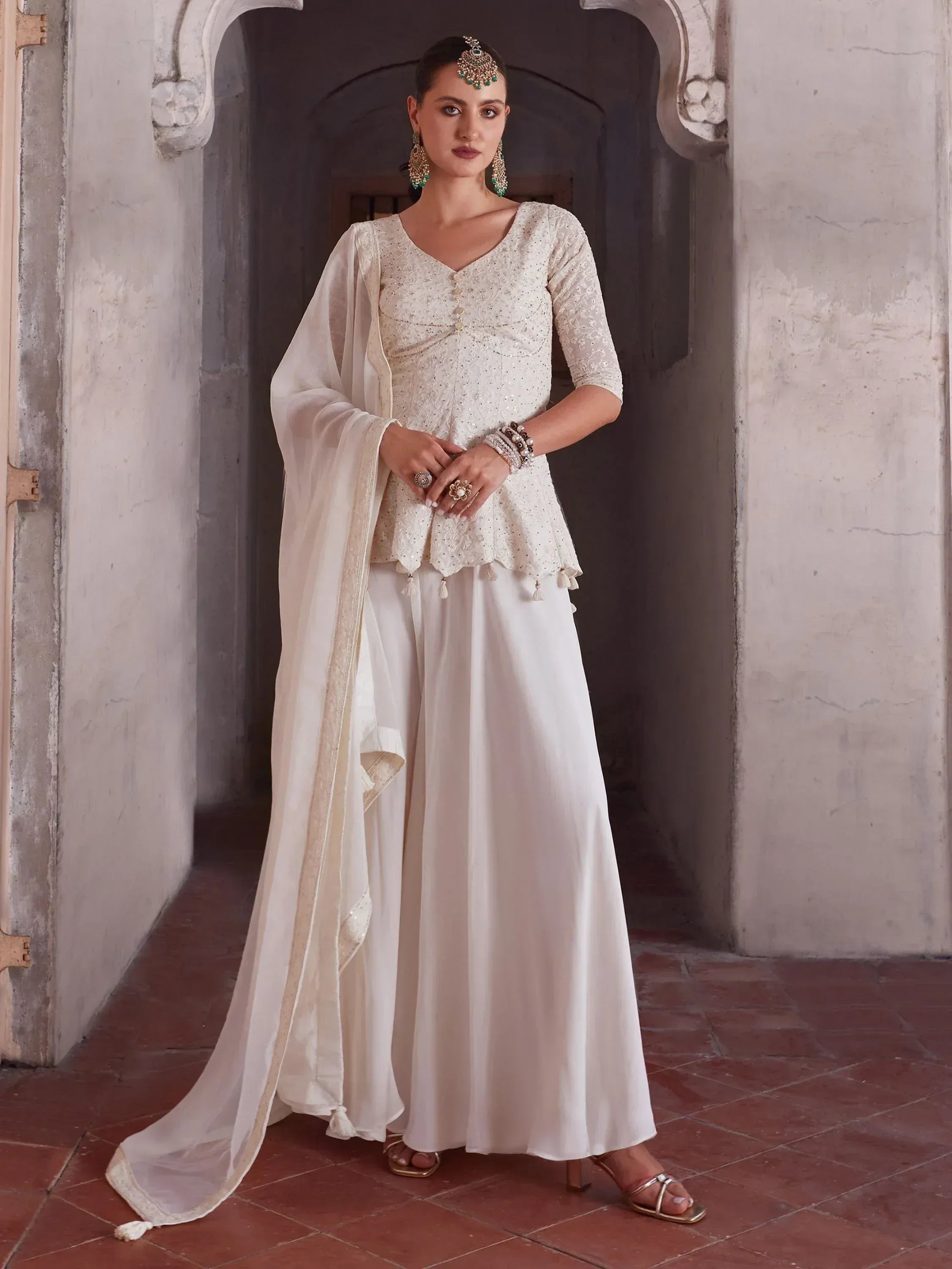 Woman wearing elegant off-white ethnic palazzo suit with dupatta and traditional jewelry
