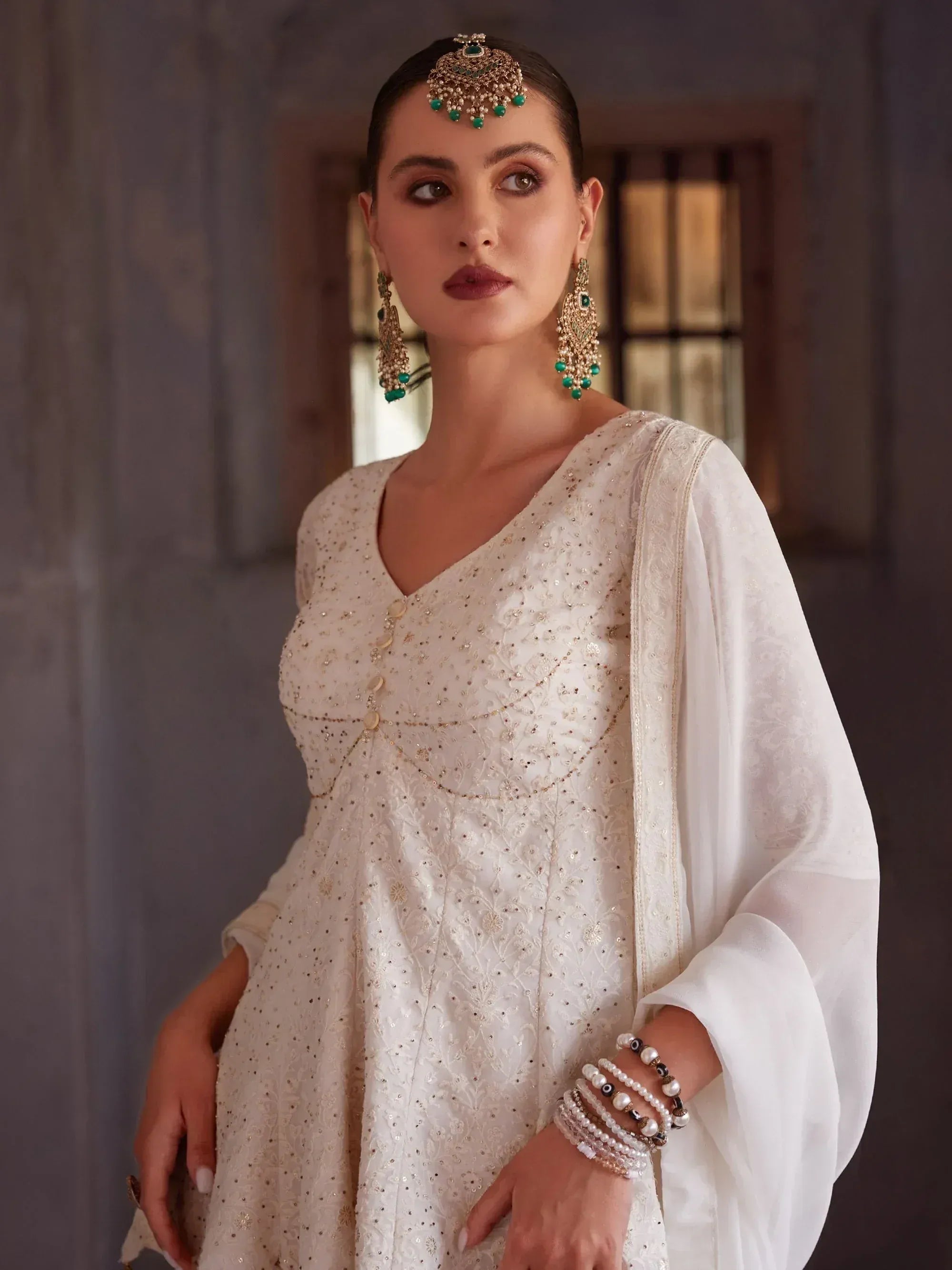 Woman in an off-white embroidered ethnic gown with traditional jewelry and sheer dupatta