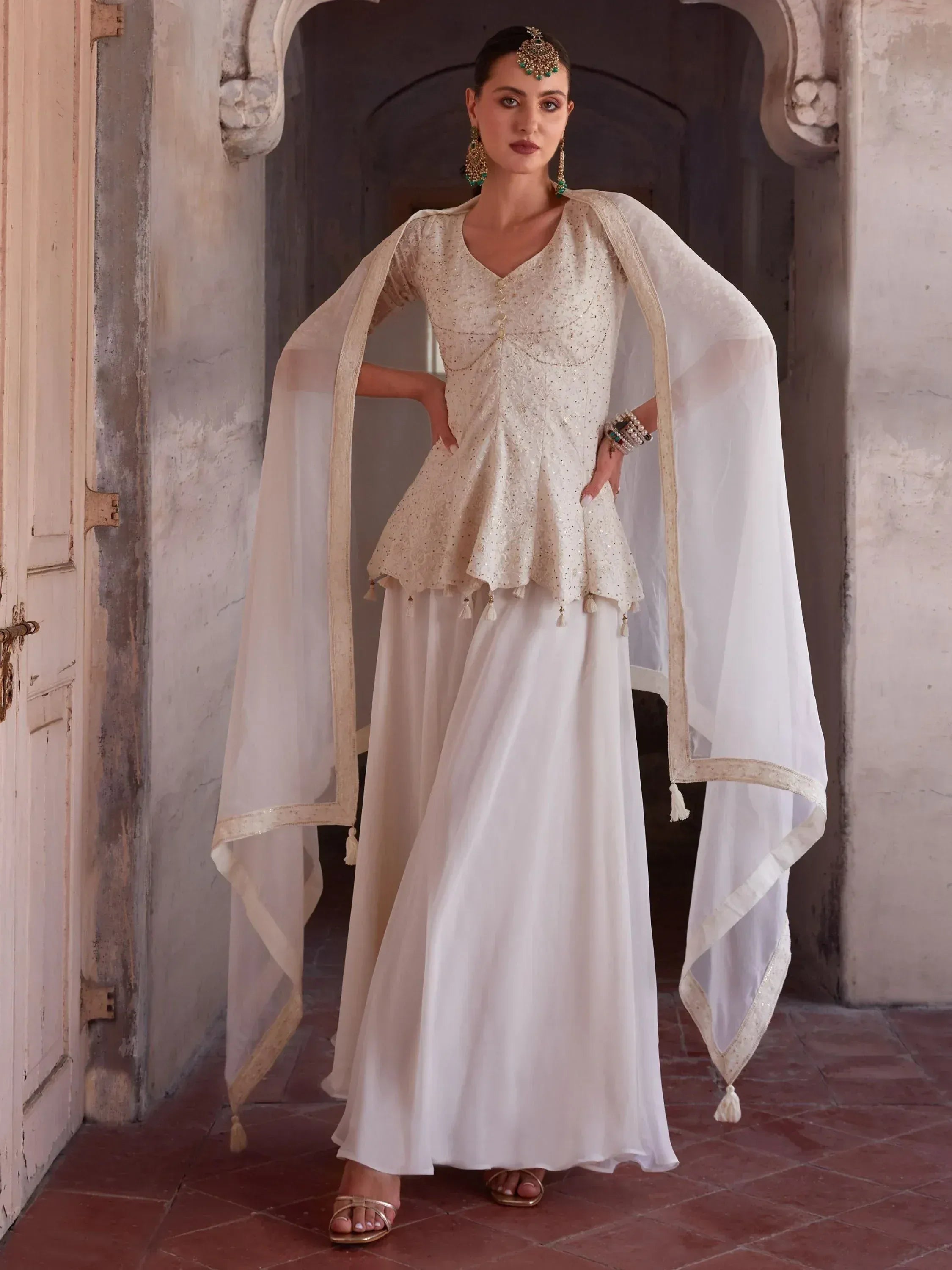 Woman wearing ivory designer lehenga choli with dupatta, traditional jewelry, ethnic wear