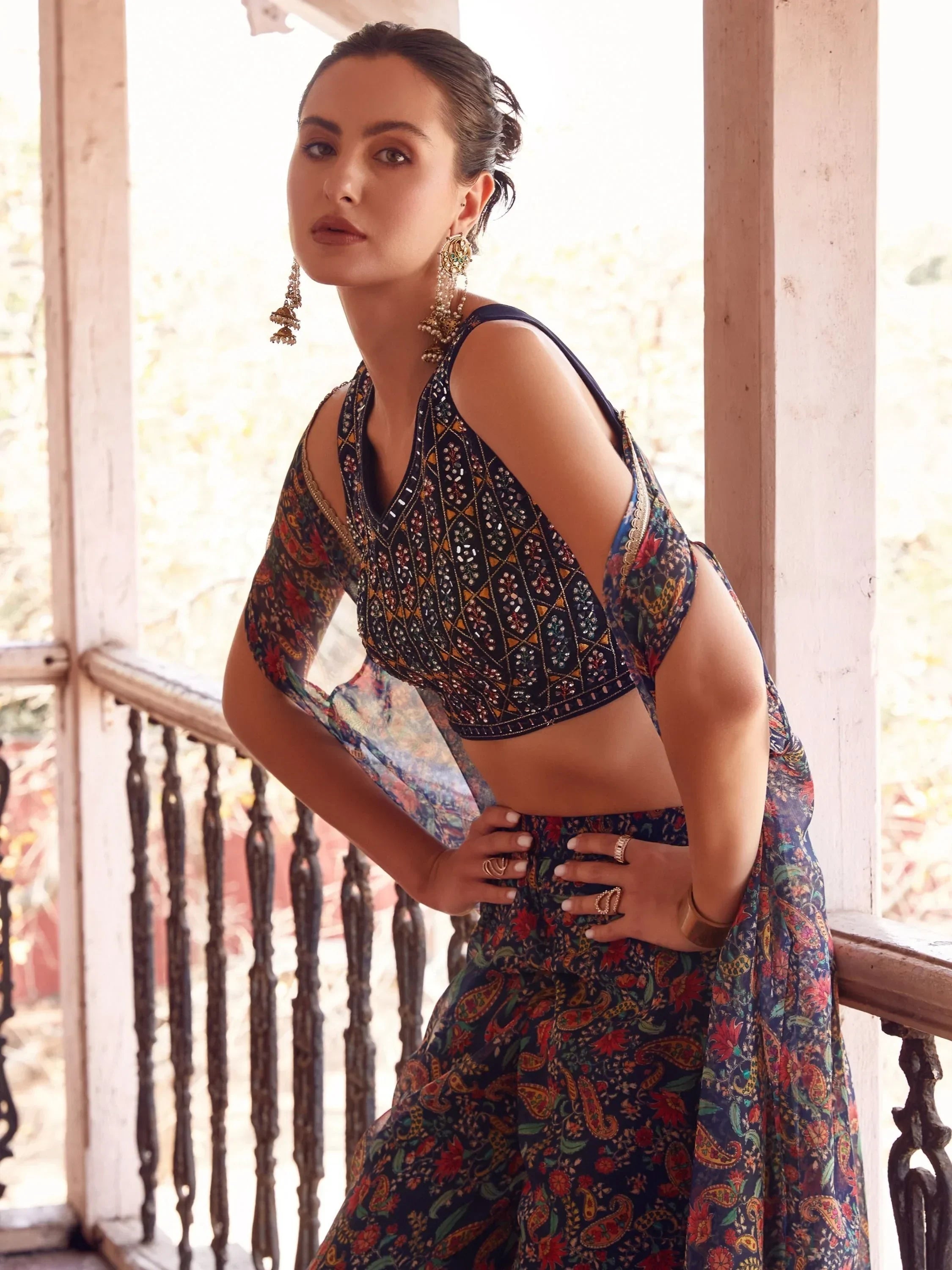 Woman wearing a navy blue printed lehenga choli with intricate patterns and statement earrings