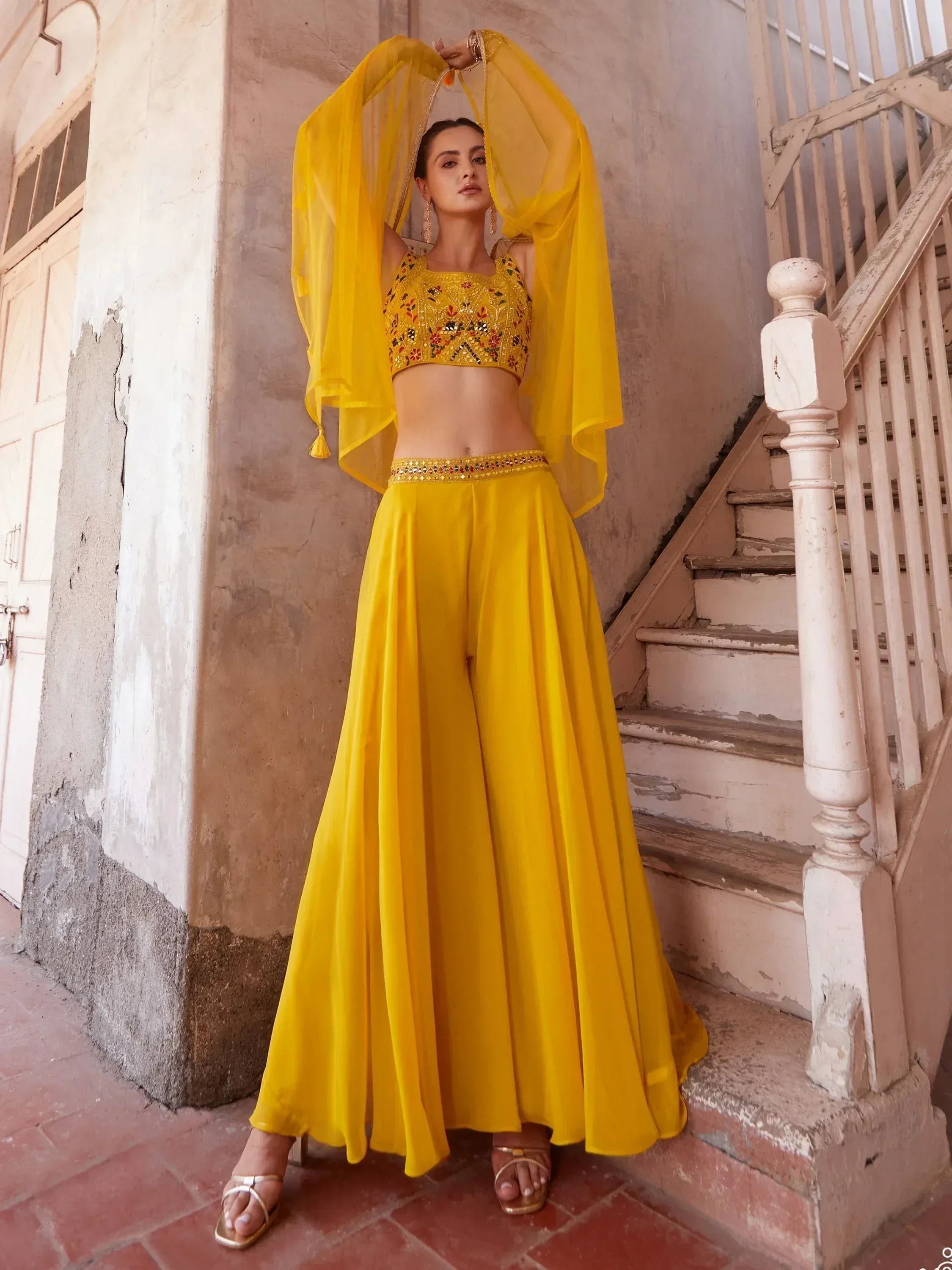 Woman wearing yellow embroidered lehenga choli set with flared palazzo pants and dupatta
