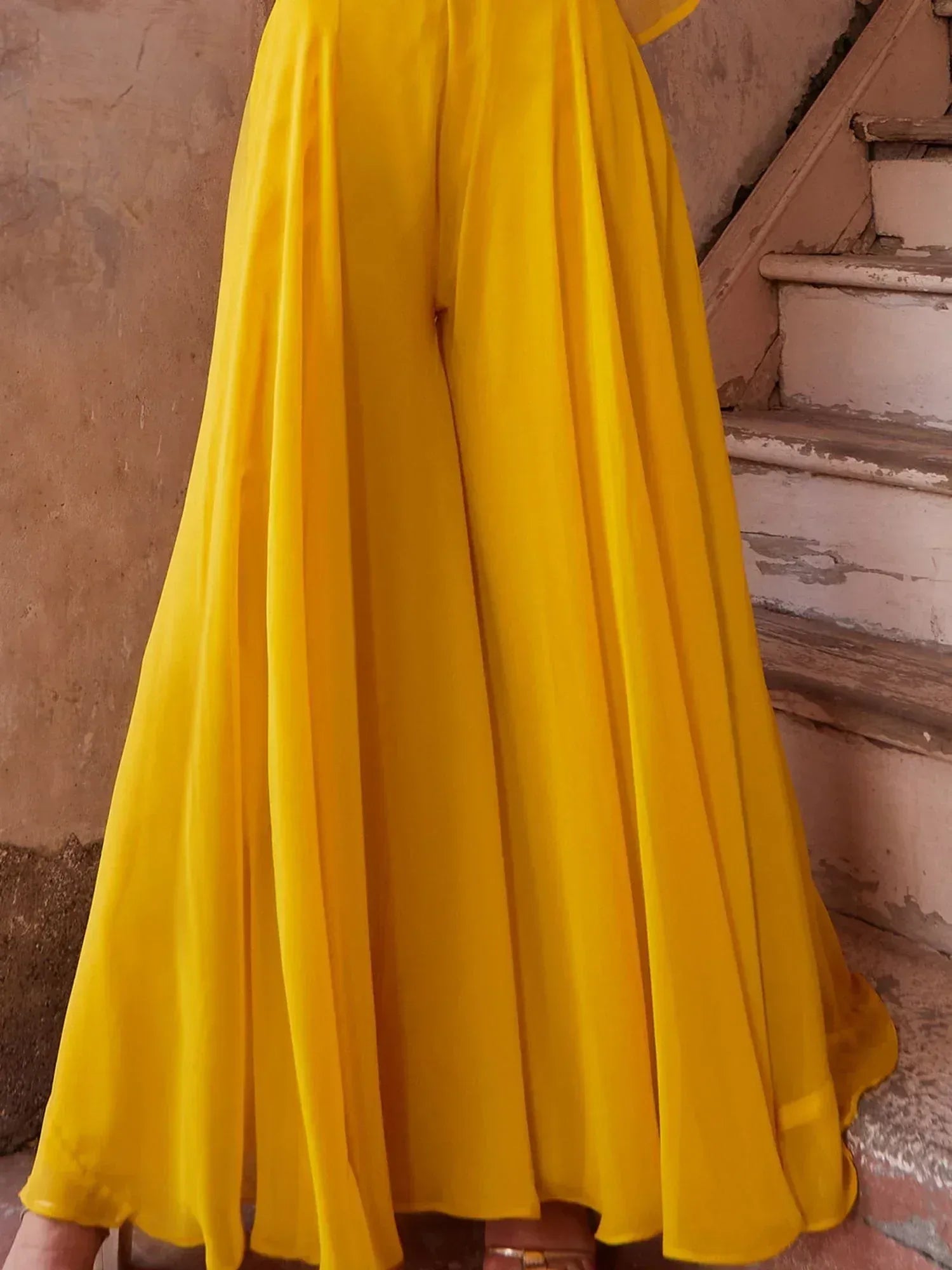 Yellow flared palazzo pants for women, flowy ethnic wear style, rustic background