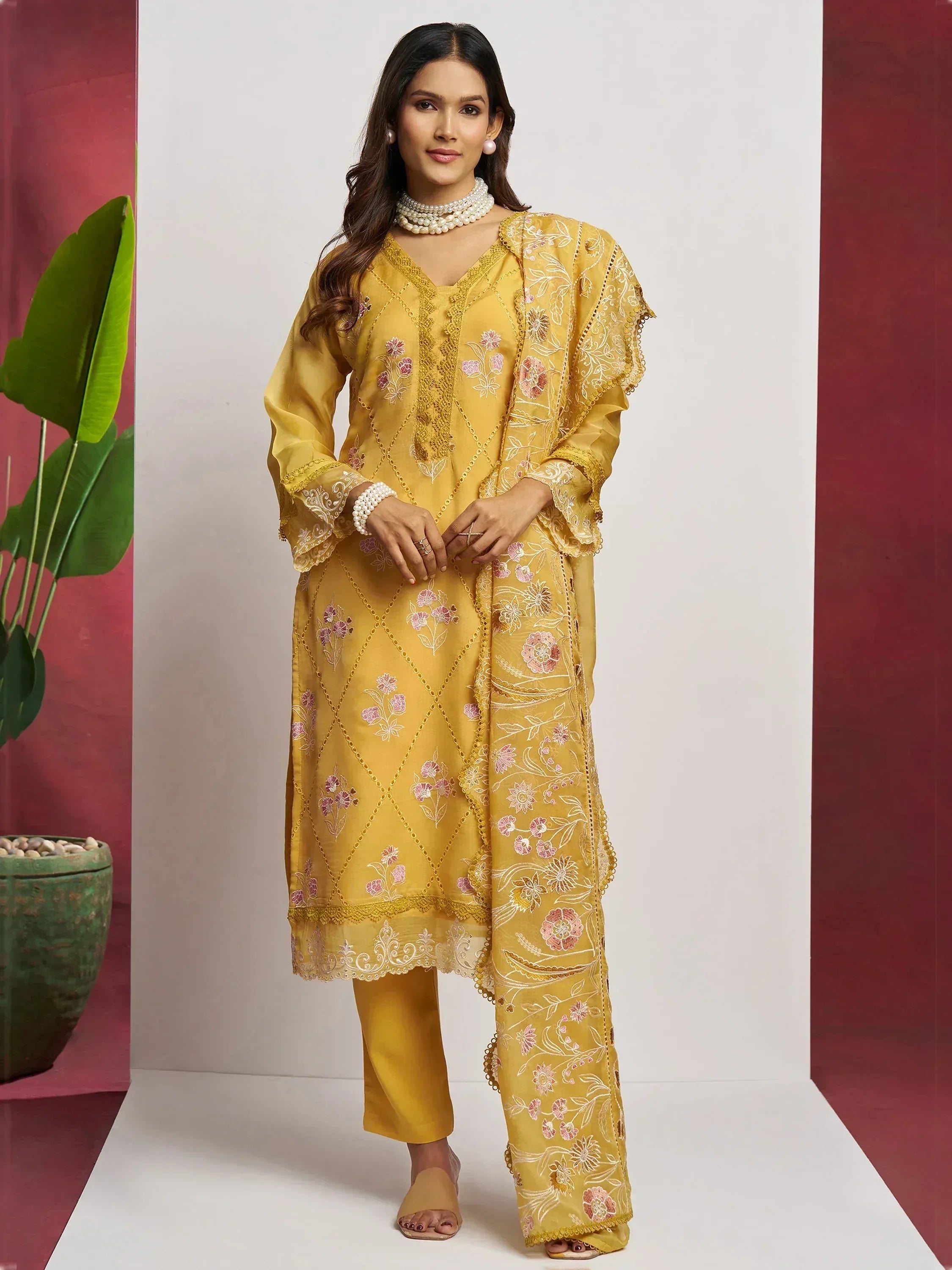 Yellow embroidered salwar kameez with floral patterns and pearl jewelry, ideal for Indian ethnic wear