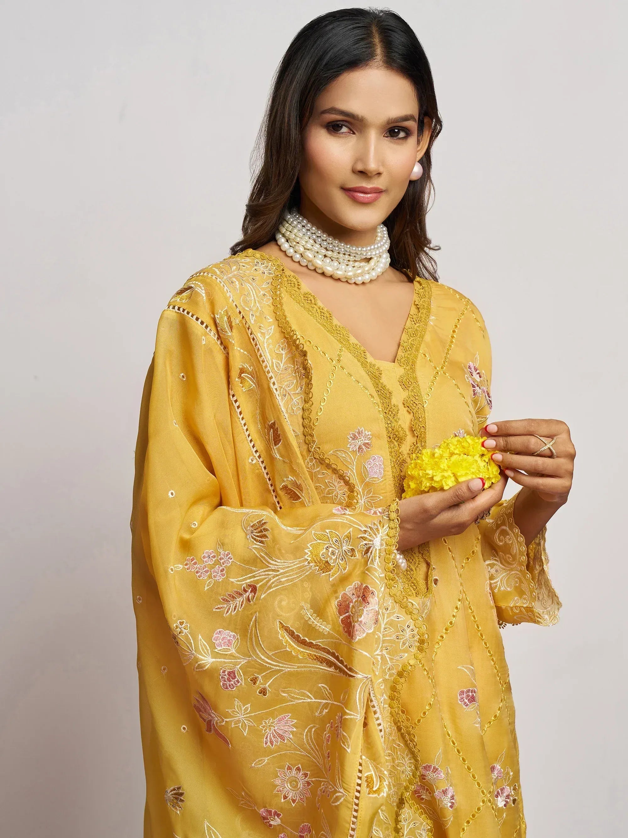 Yellow embroidered ethnic gown with floral design, paired with pearl jewelry for festive occasions