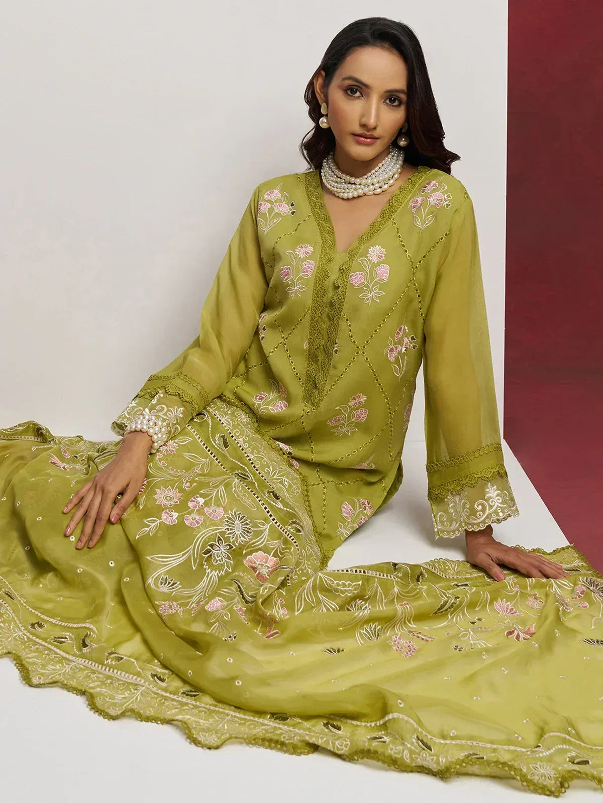 Olive green embroidered salwar kameez with floral motifs and pearl jewelry, perfect for ethnic occasions.