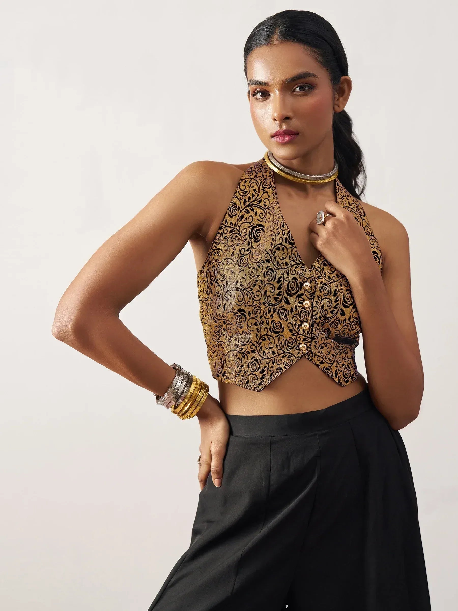 Gold and black floral halter neck crop top with buttons, paired with black pants for ethnic wear