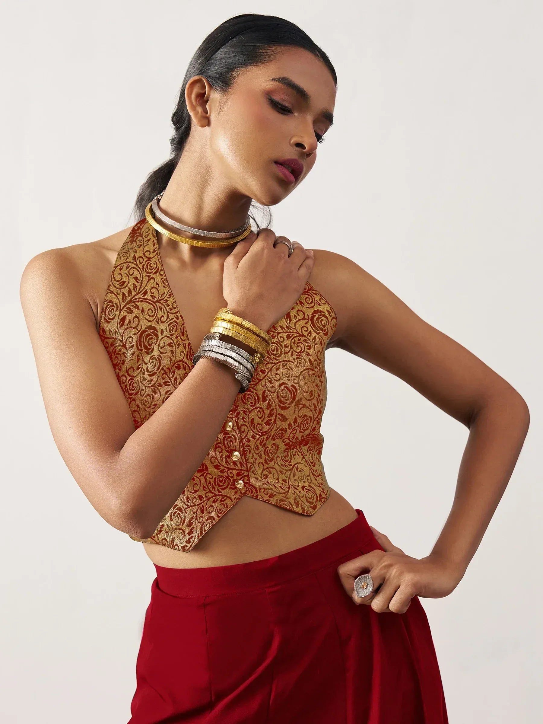 Woman in ethnic gold floral blouse with red skirt, styled with choker and bangles for Indian wear