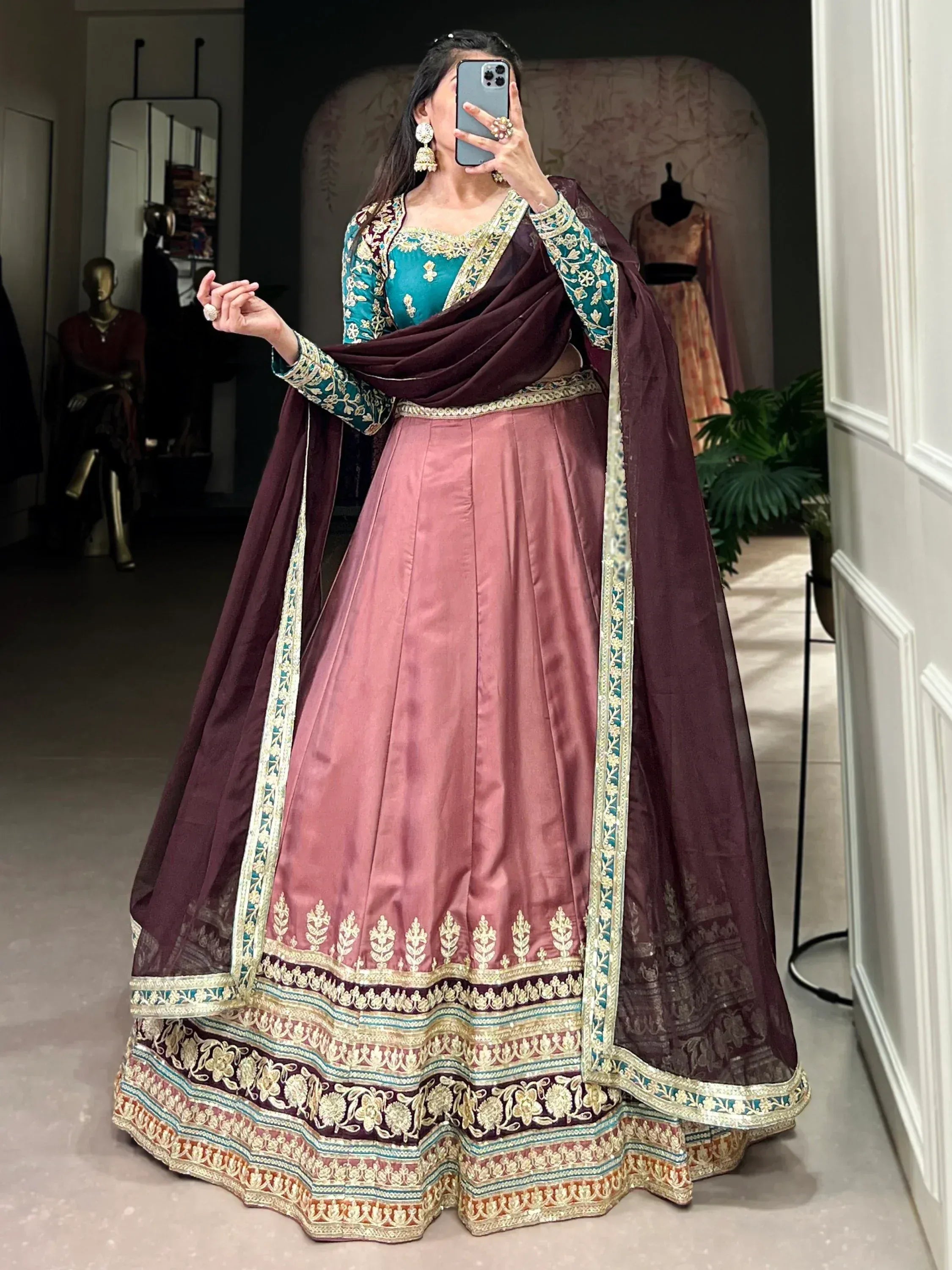 Woman in designer lehenga choli with teal blouse, dusty pink skirt, and maroon dupatta, perfect for Indian ethnic wear events.