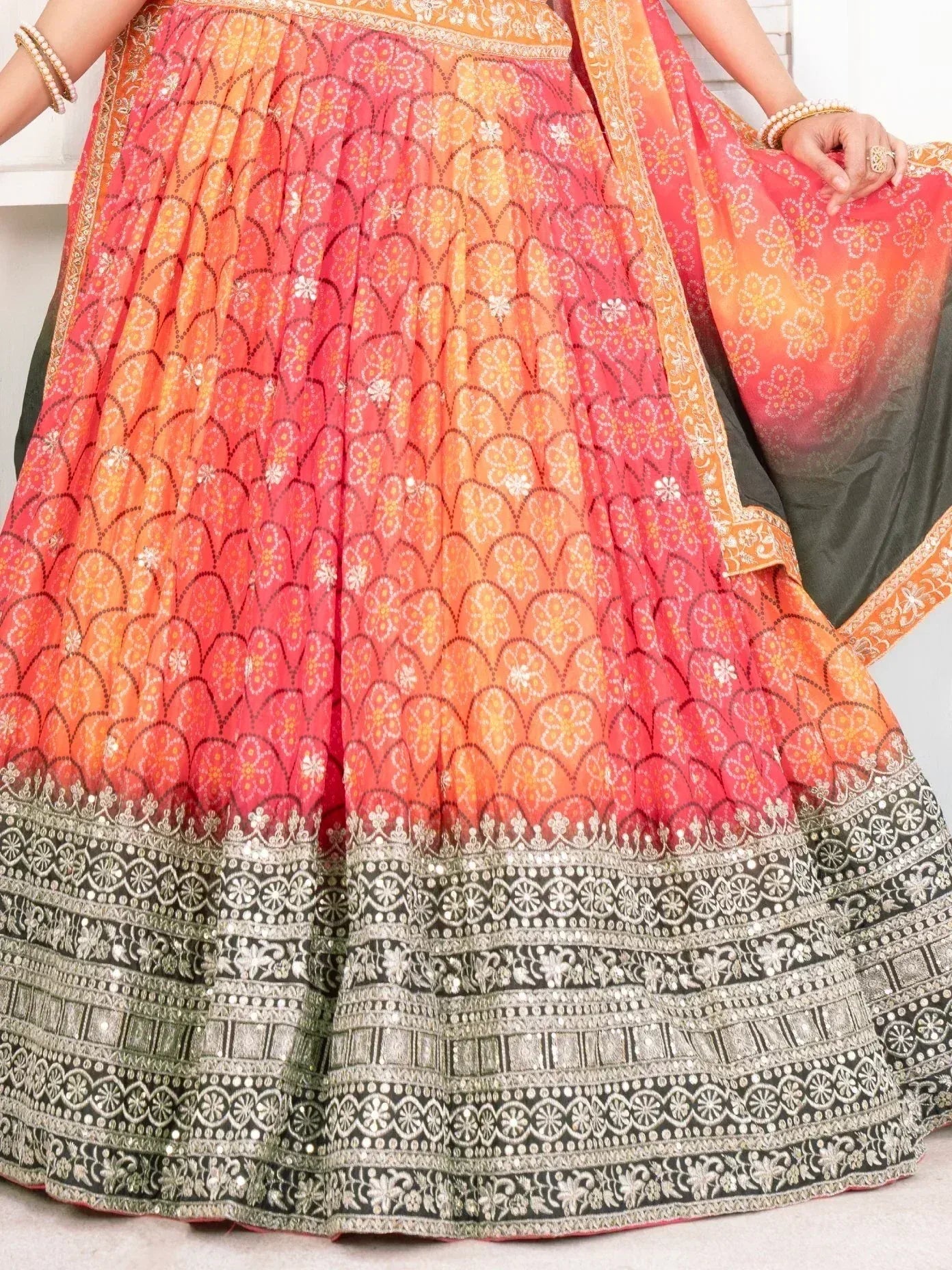 Vibrant orange-pink lehenga choli with floral print and silver embroidery, perfect for Indian ethnic wear.
