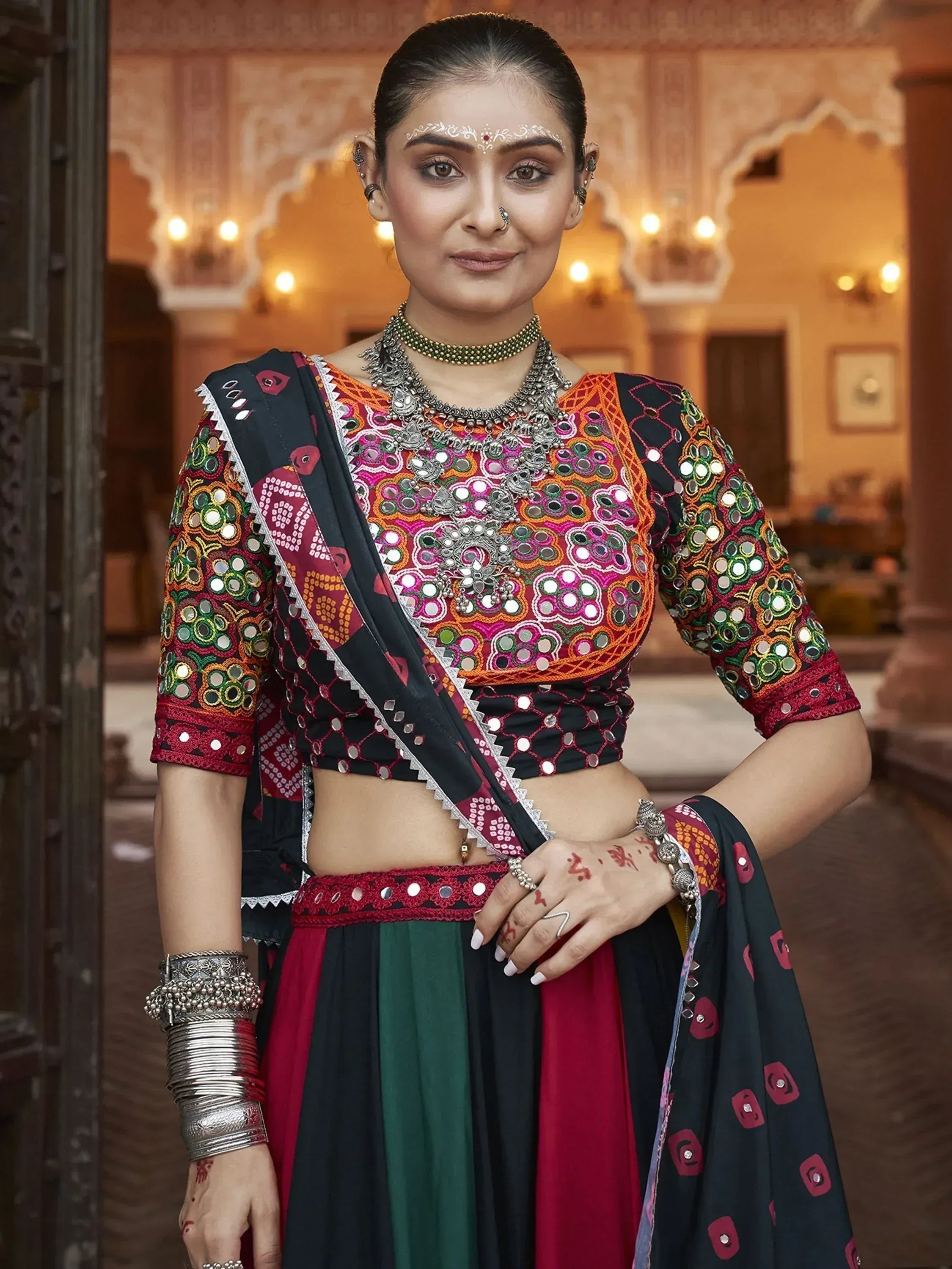 Woman in colorful mirror-work lehenga choli with traditional jewelry, perfect for Indian ethnic wear occasions