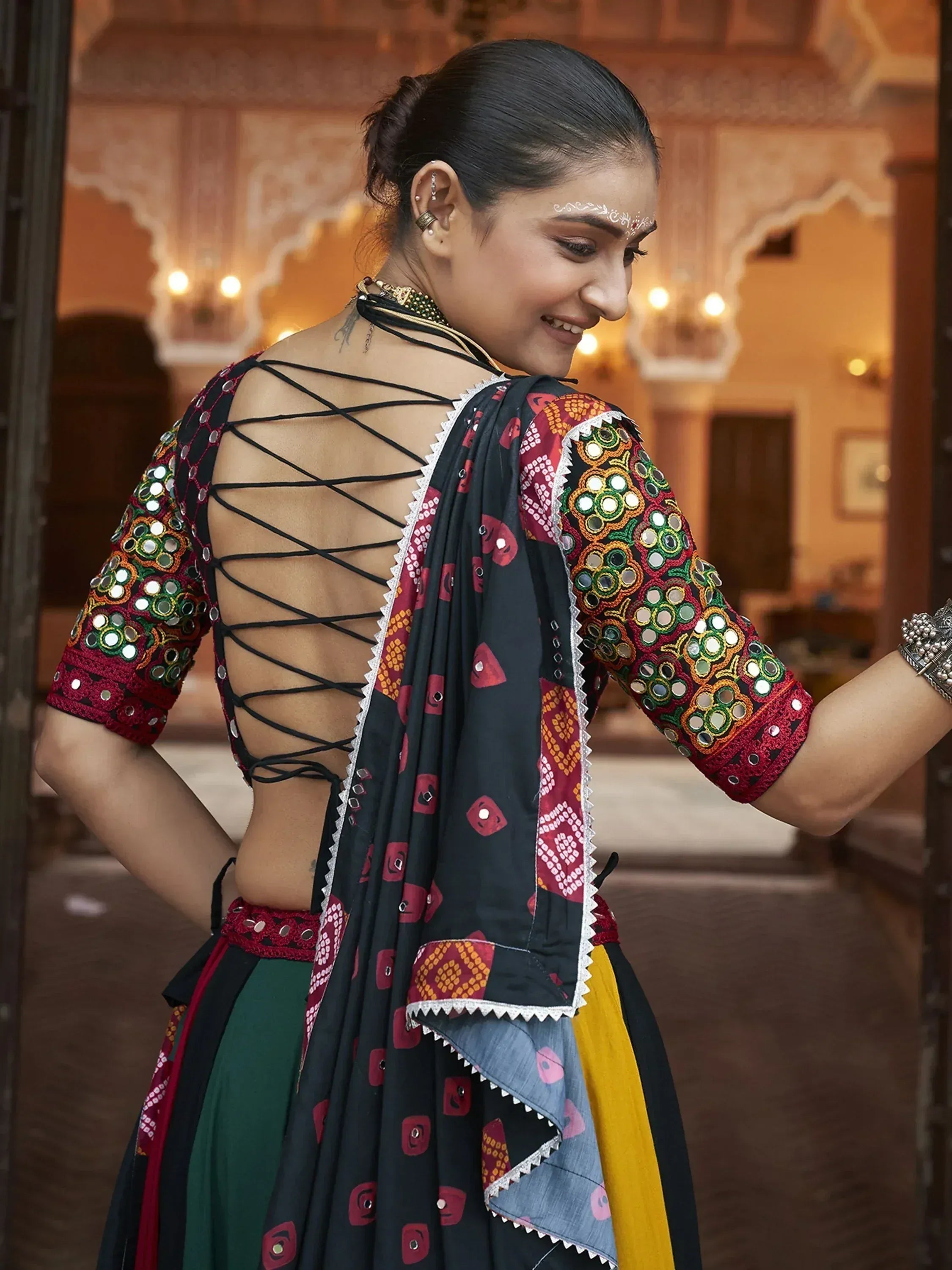 Woman in colorful mirror-work ethnic lehenga choli with crisscross back design, traditional Indian attire