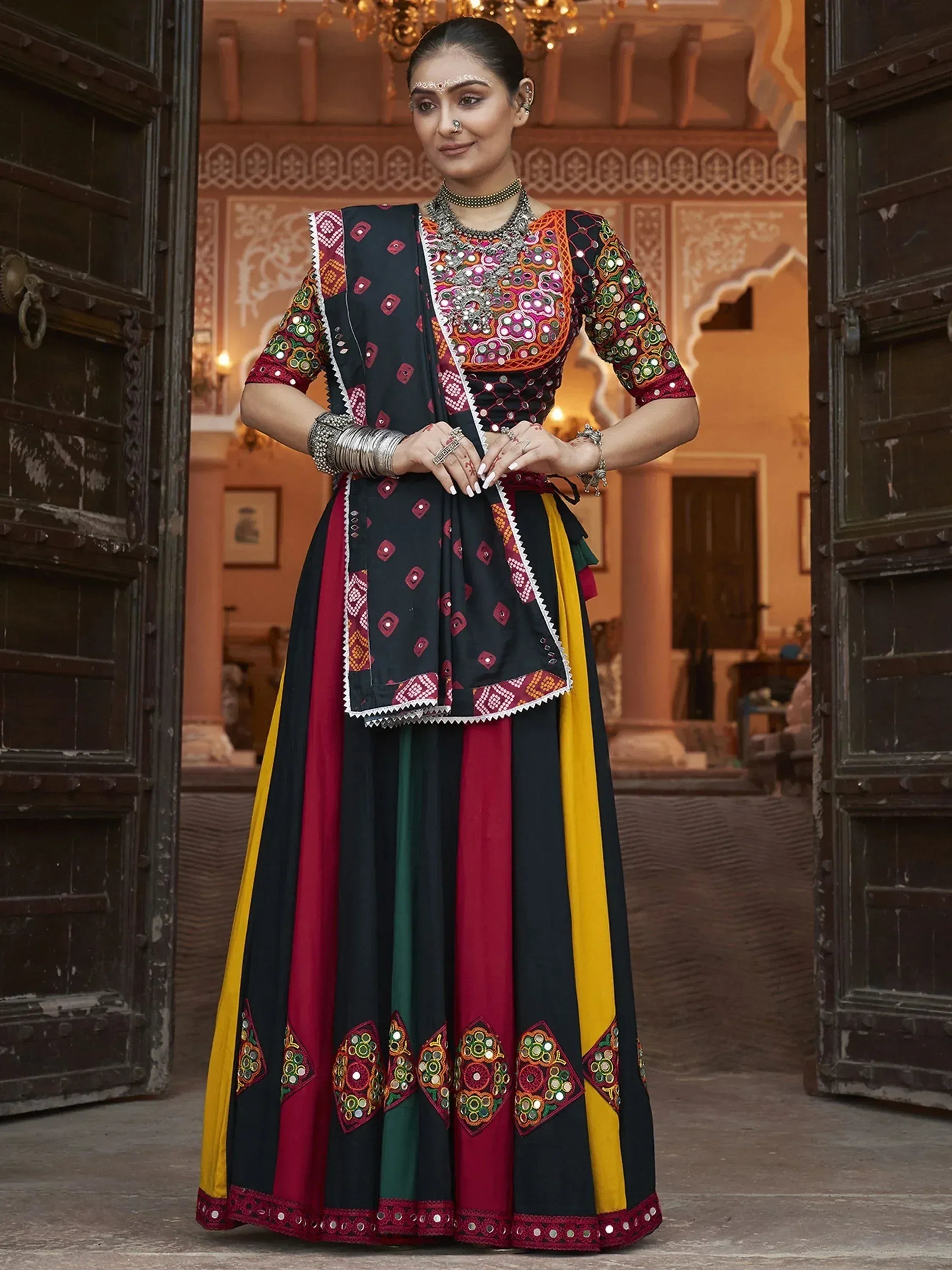 Woman in colorful Indian ethnic wear with mirror work, standing in traditional doorway