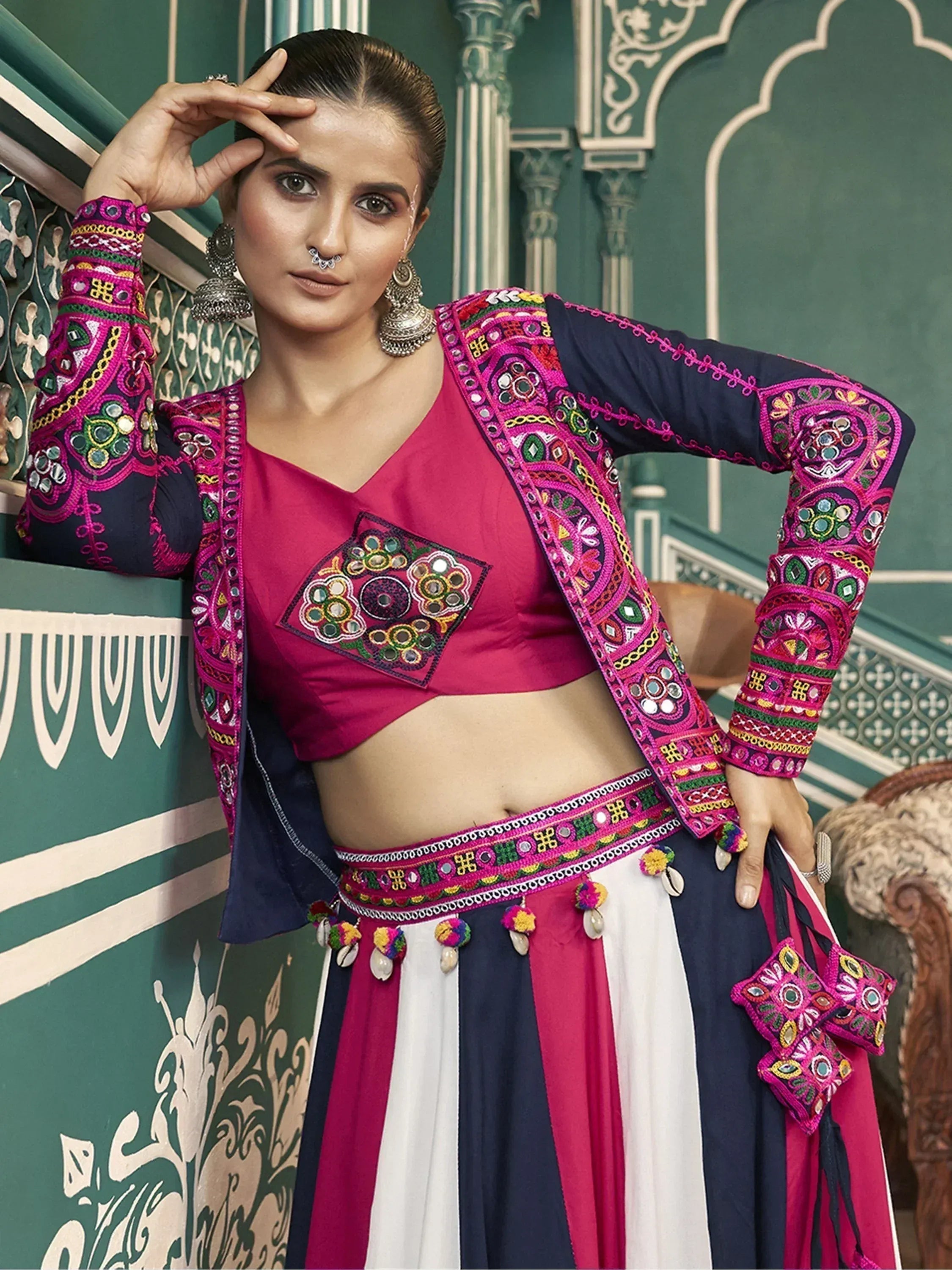 Woman in vibrant Indian ethnic wear with mirror work, embroidered jacket, and striped skirt
