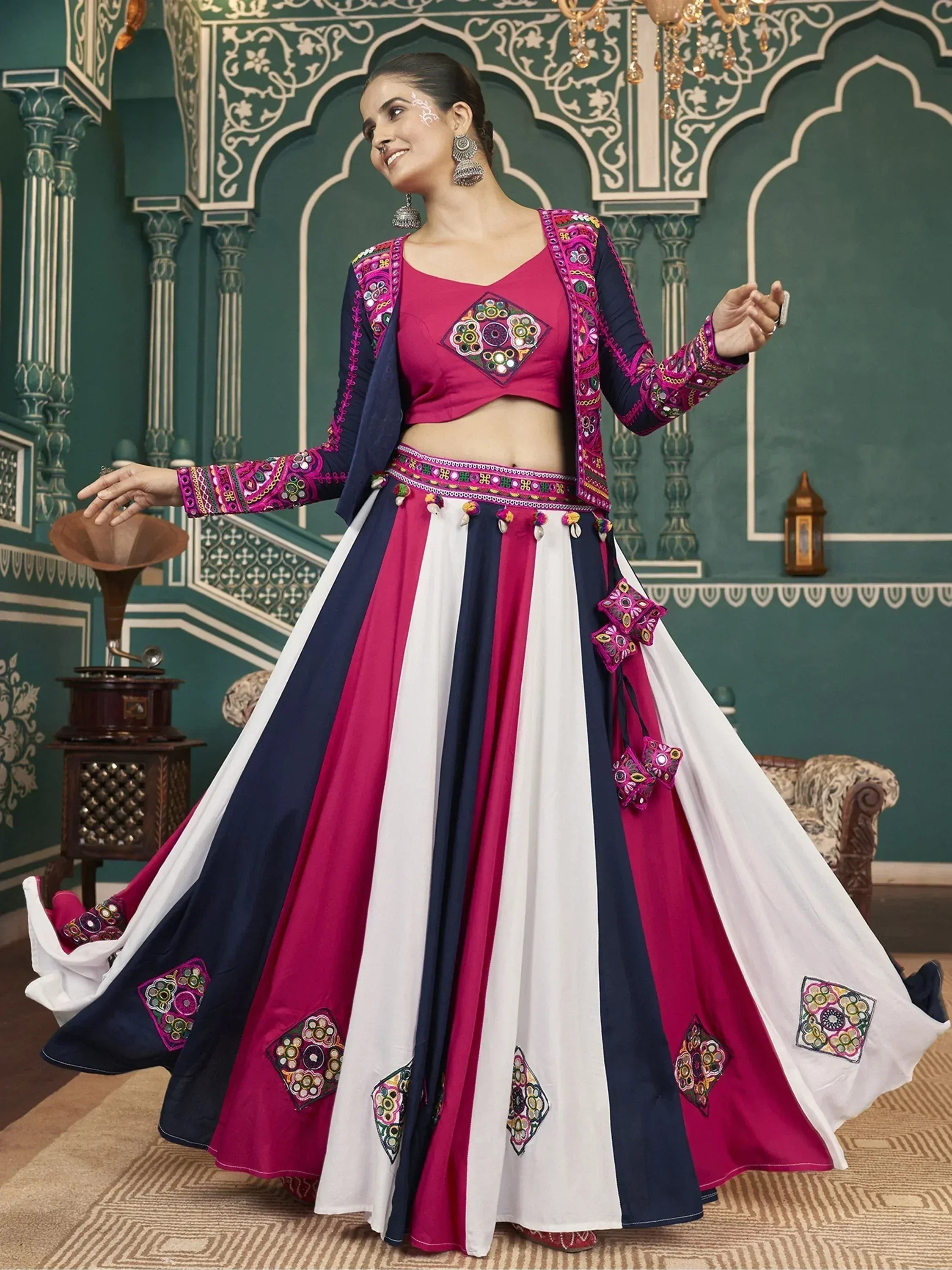 Woman in vibrant pink, white, and navy ethnic lehenga choli with mirror work, perfect for Indian festivals and weddings.
