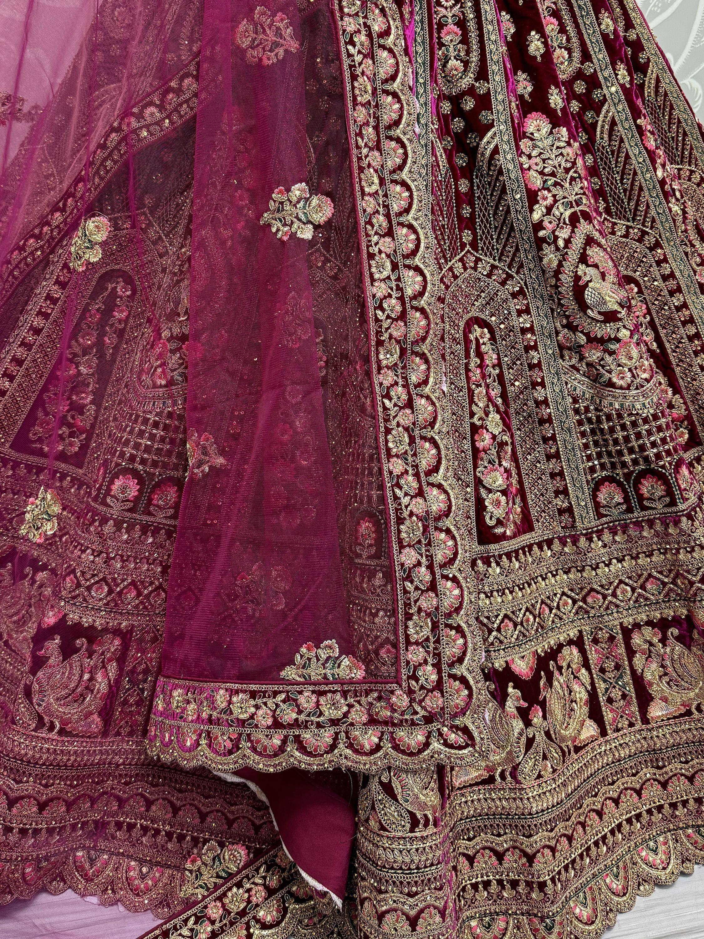 Luxury maroon velvet lehenga with intricate gold embroidery and floral motifs, perfect for Indian weddings.
