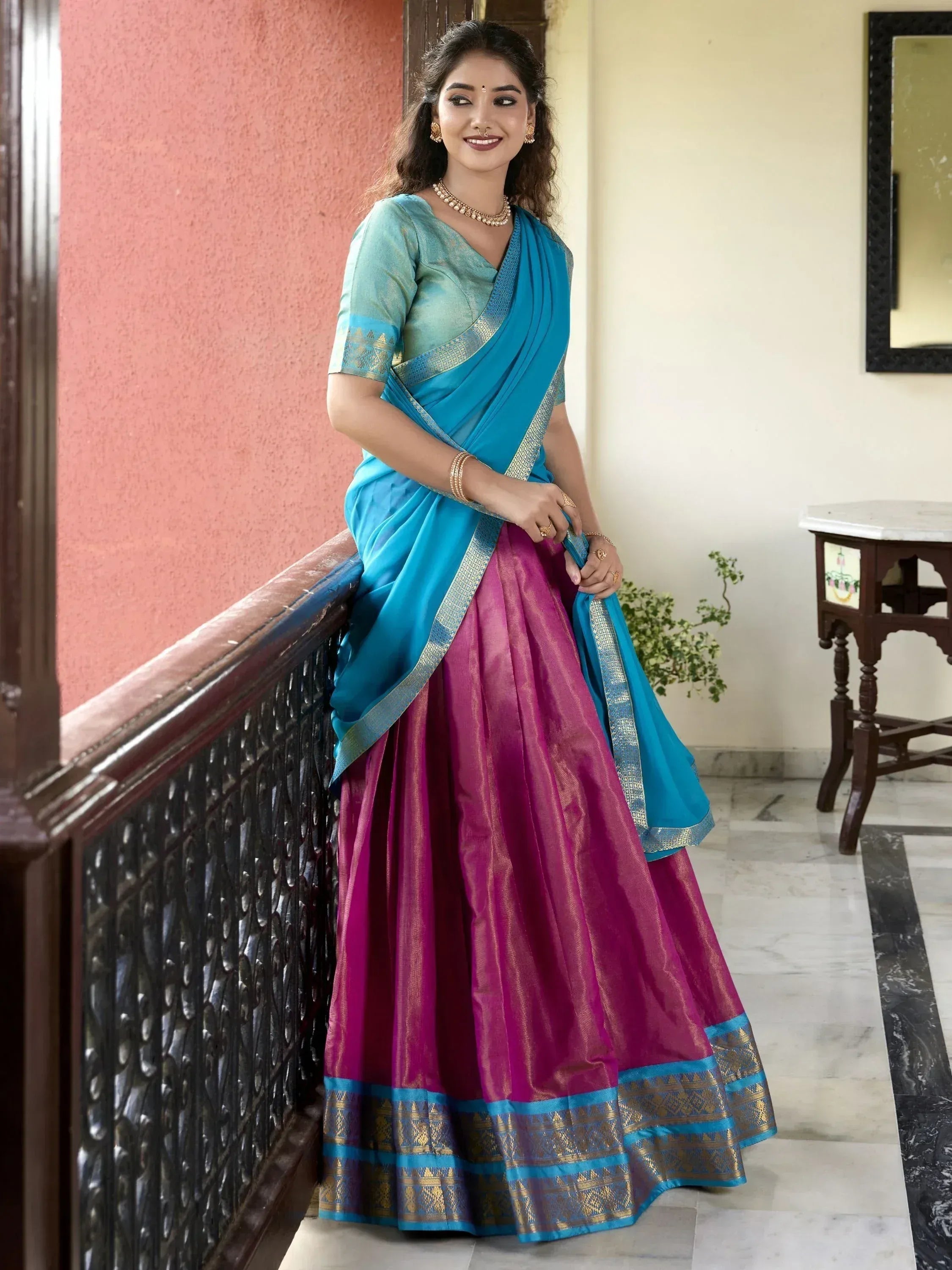 Woman in vibrant blue and magenta designer lehenga choli with gold border, perfect for Indian ethnic wear occasions