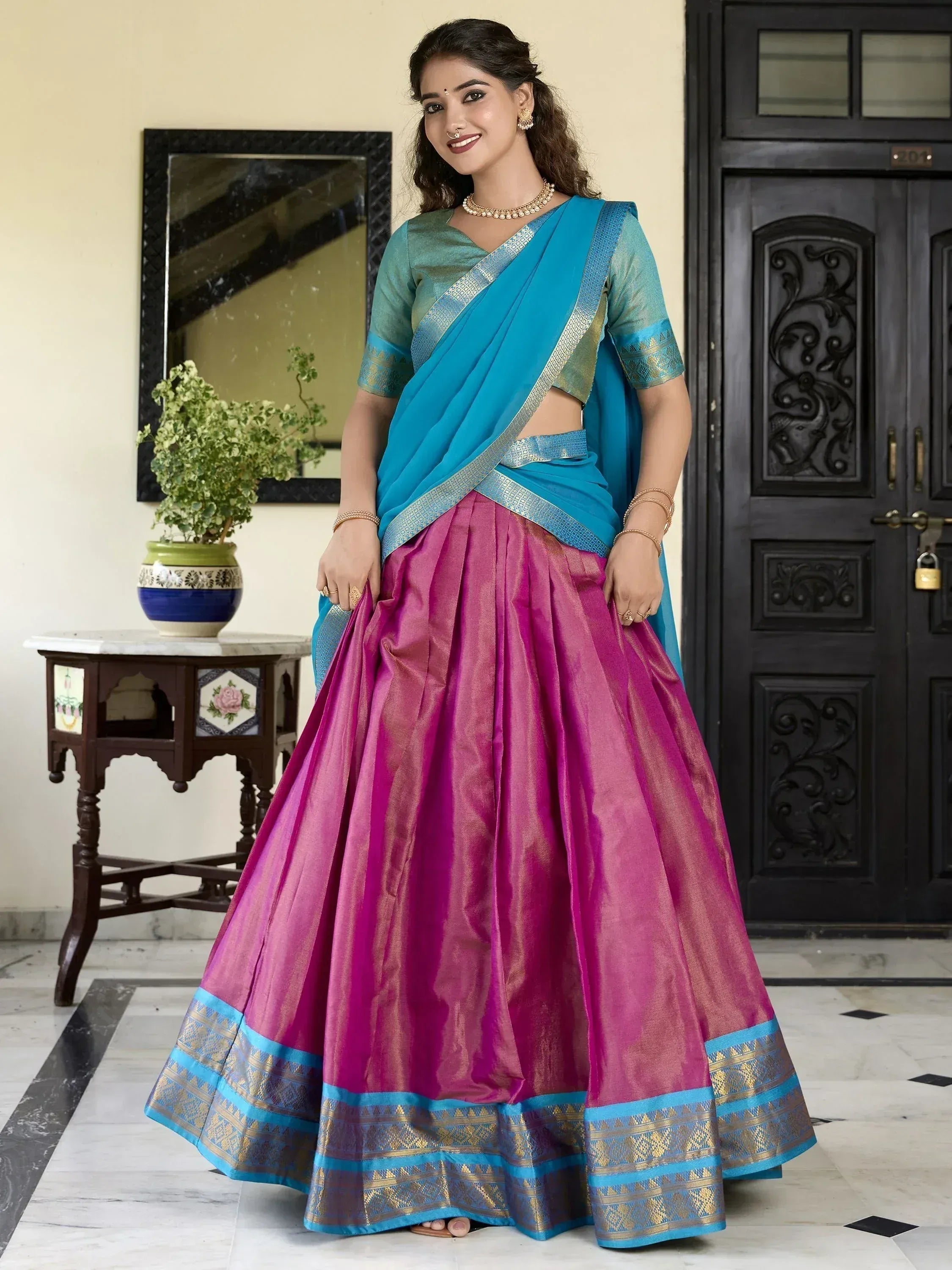 Woman in vibrant pink and blue designer lehenga choli with gold border, perfect for Indian ethnic occasions