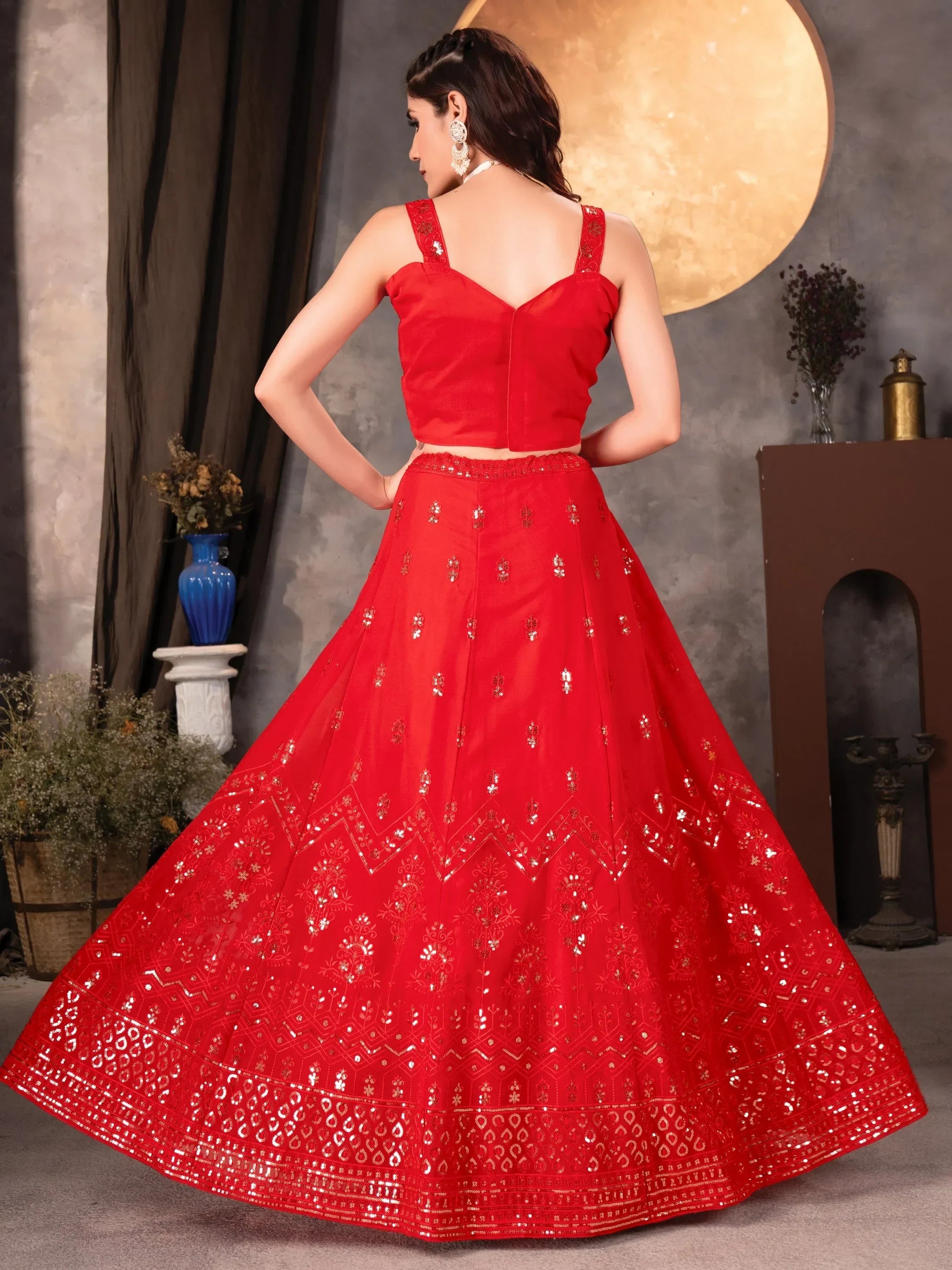 Red designer lehenga choli with intricate gold embroidery and mirror work, perfect for Indian ethnic occasions.