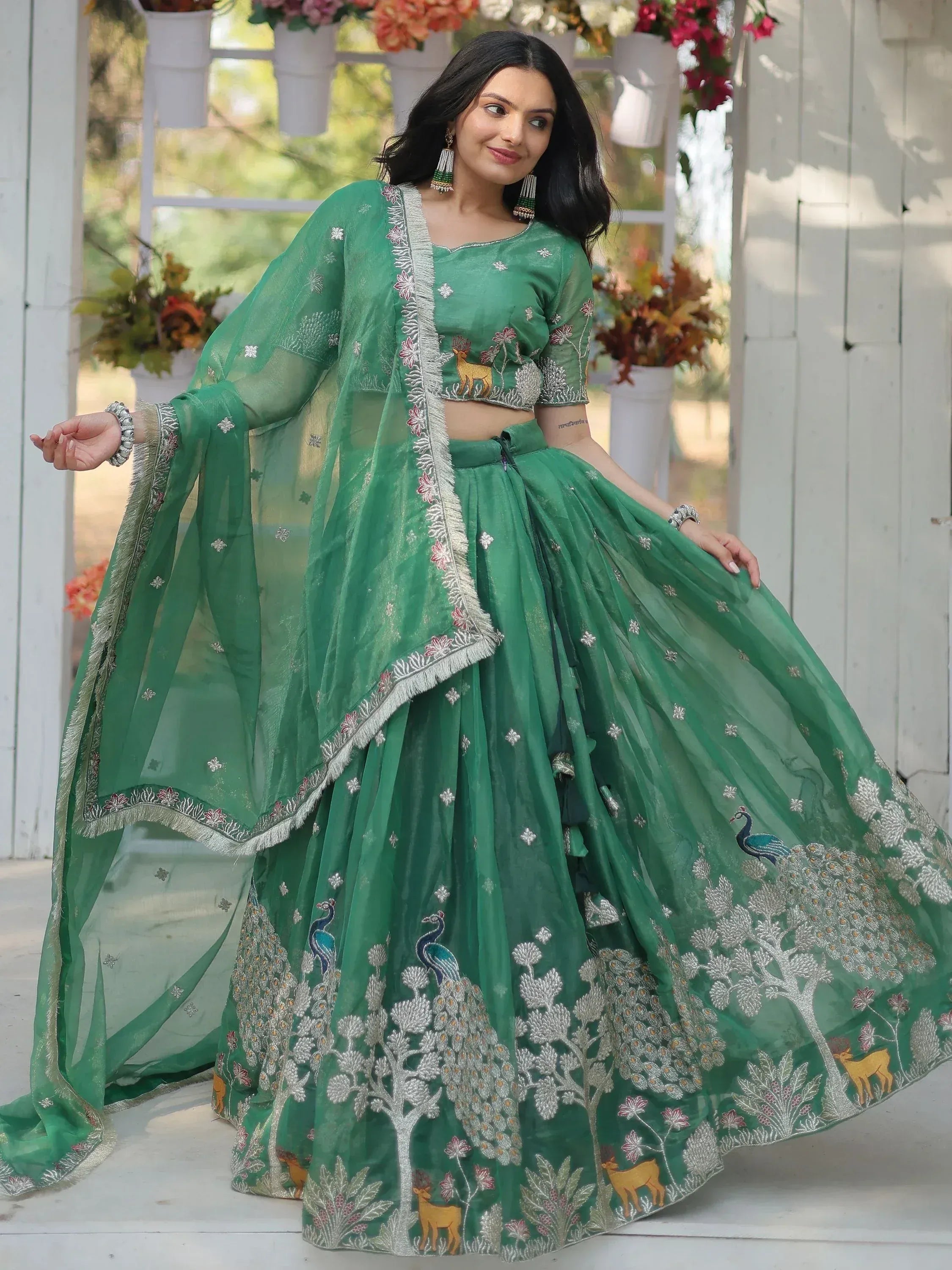 Green embroidered lehenga choli with peacock and deer motifs, perfect for Indian ethnic wear occasions.
