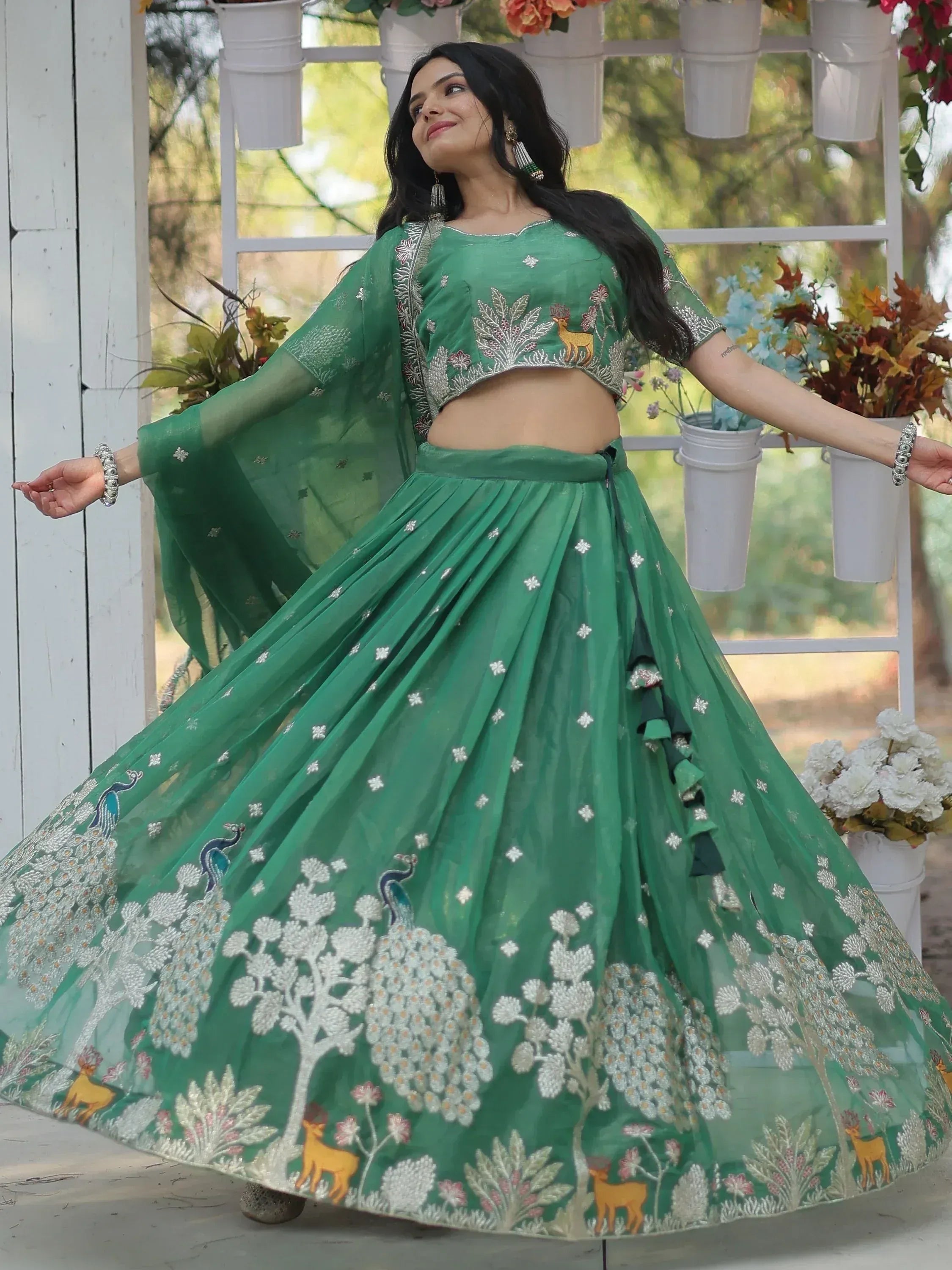 Green embroidered lehenga choli with deer and peacock motifs, perfect for Indian ethnic wear occasions.