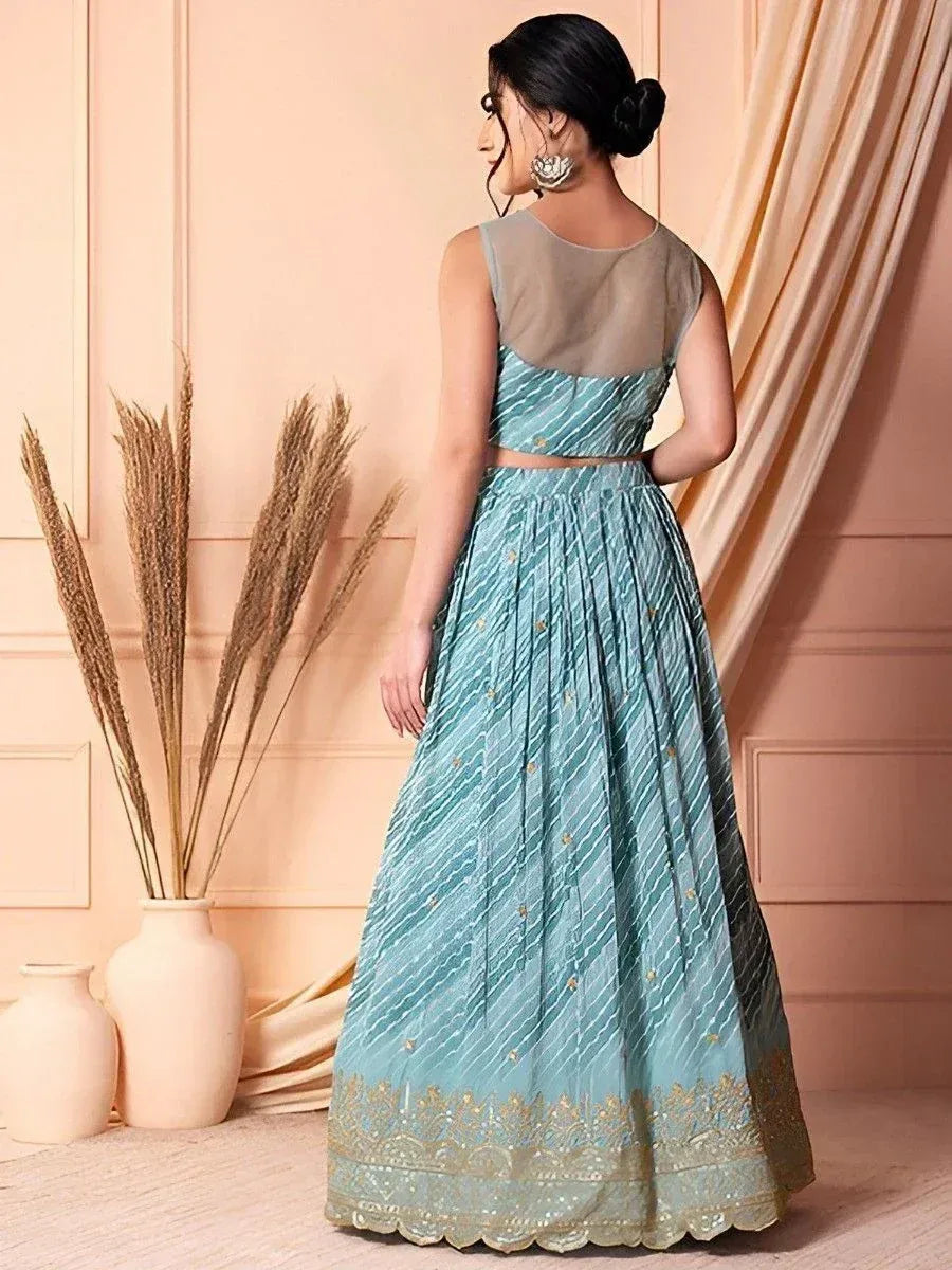 Teal designer lehenga choli with gold embroidery and sheer back, perfect for Indian ethnic wear occasions.