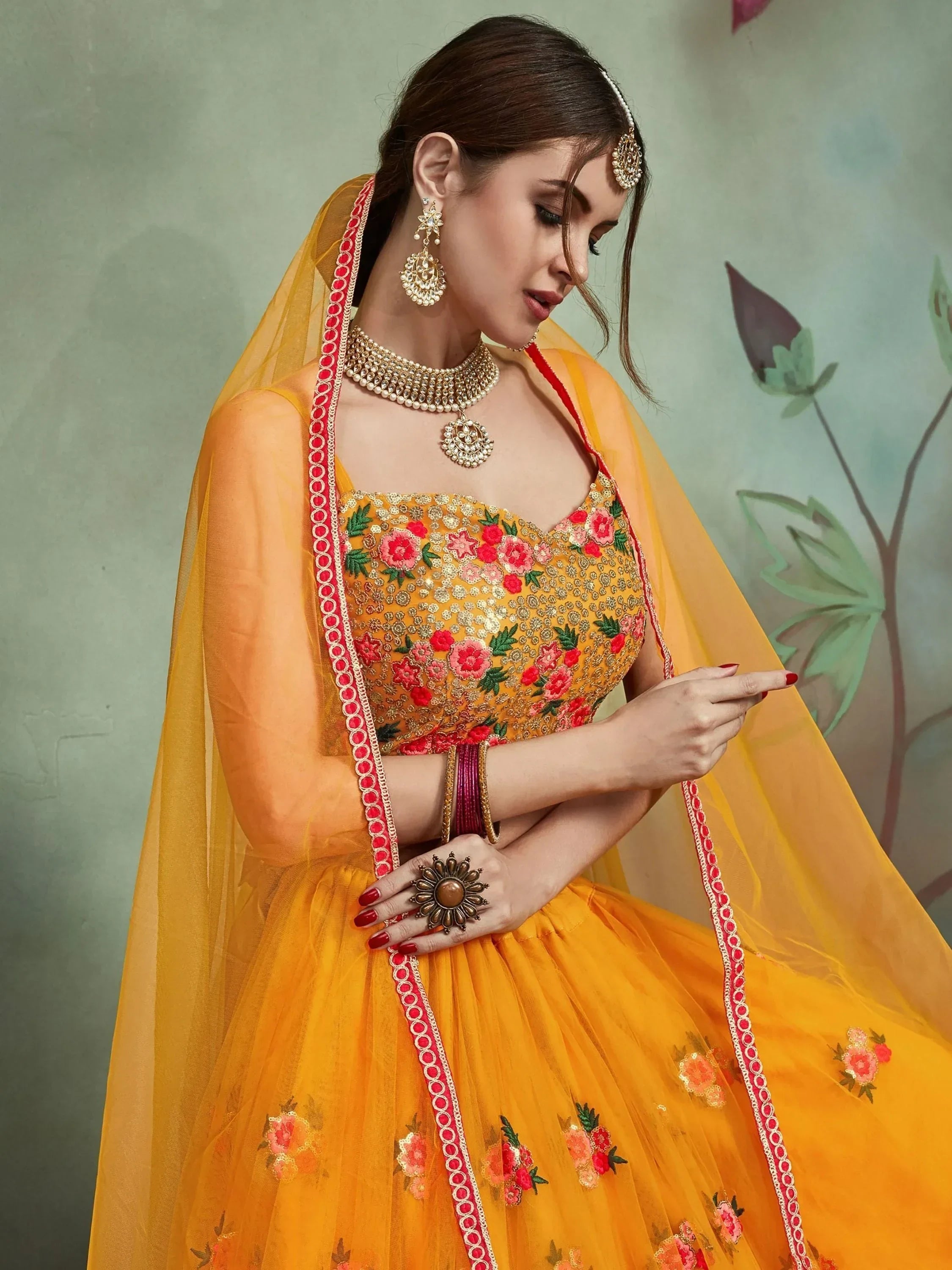 Yellow floral embroidered lehenga choli with red border, perfect for Indian weddings and festive occasions.