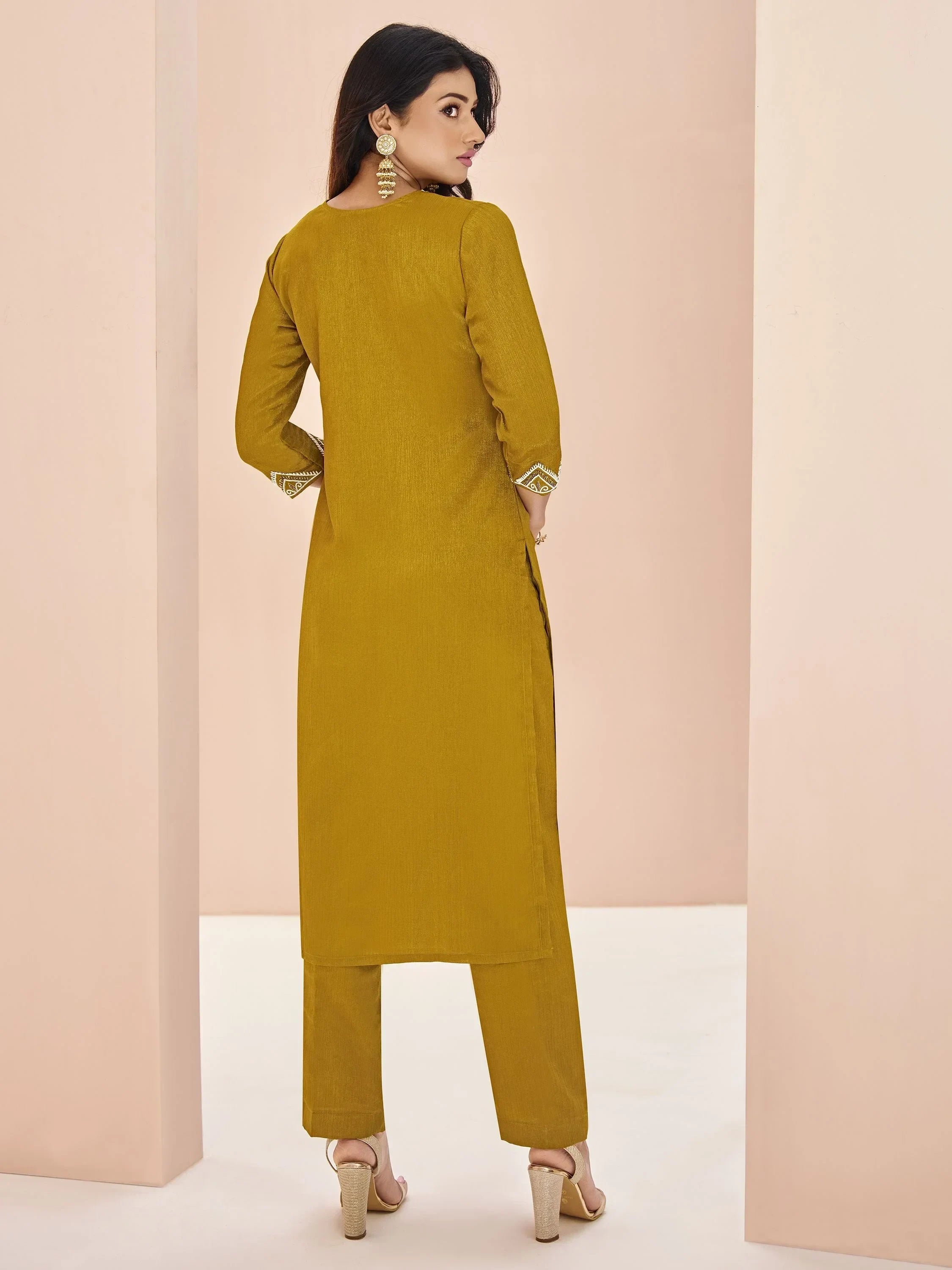 Woman in mustard yellow straight cut kurta set with pants and statement earrings