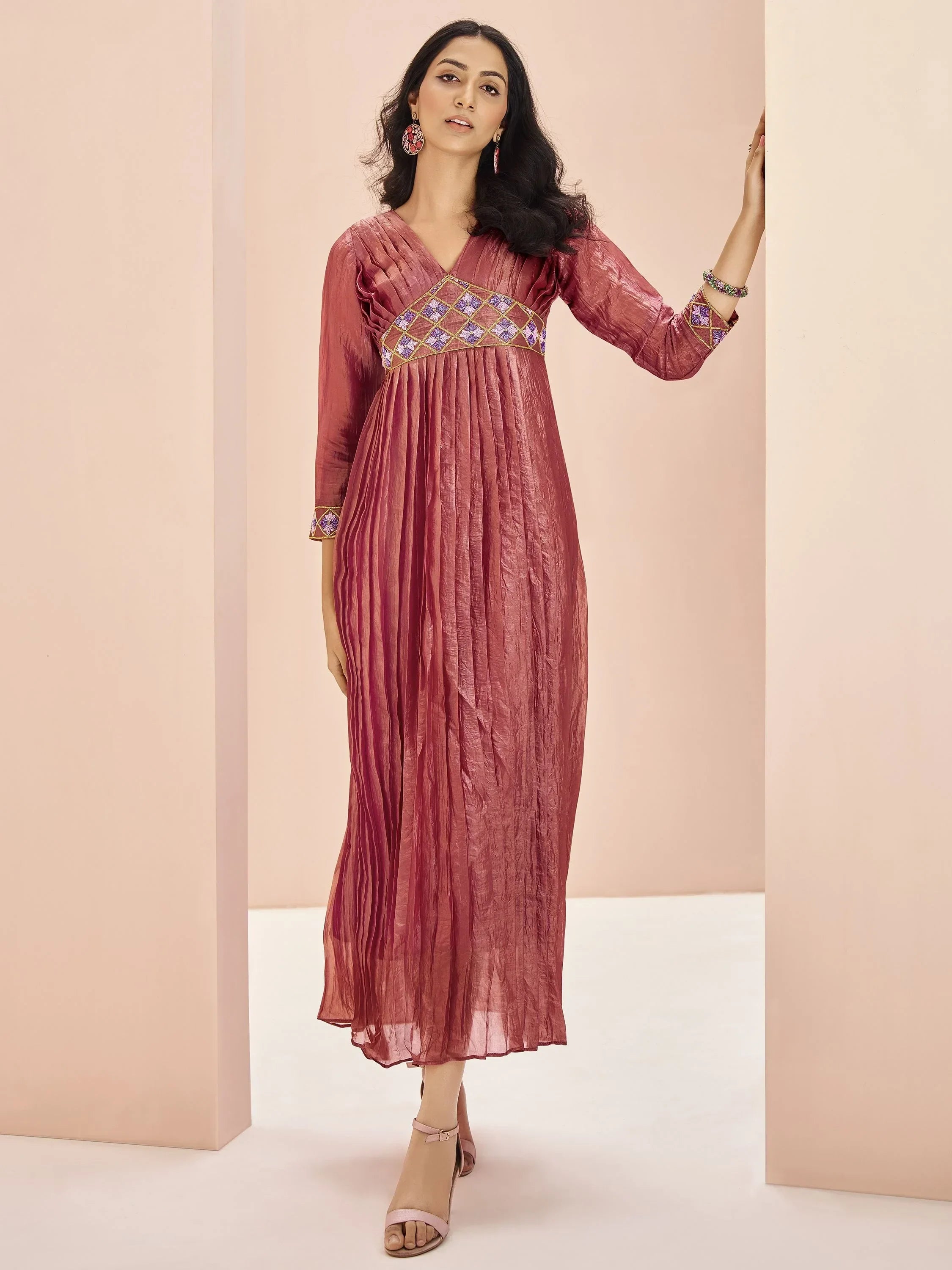Woman wearing a maroon pleated ethnic gown with embroidered details and three-quarter sleeves