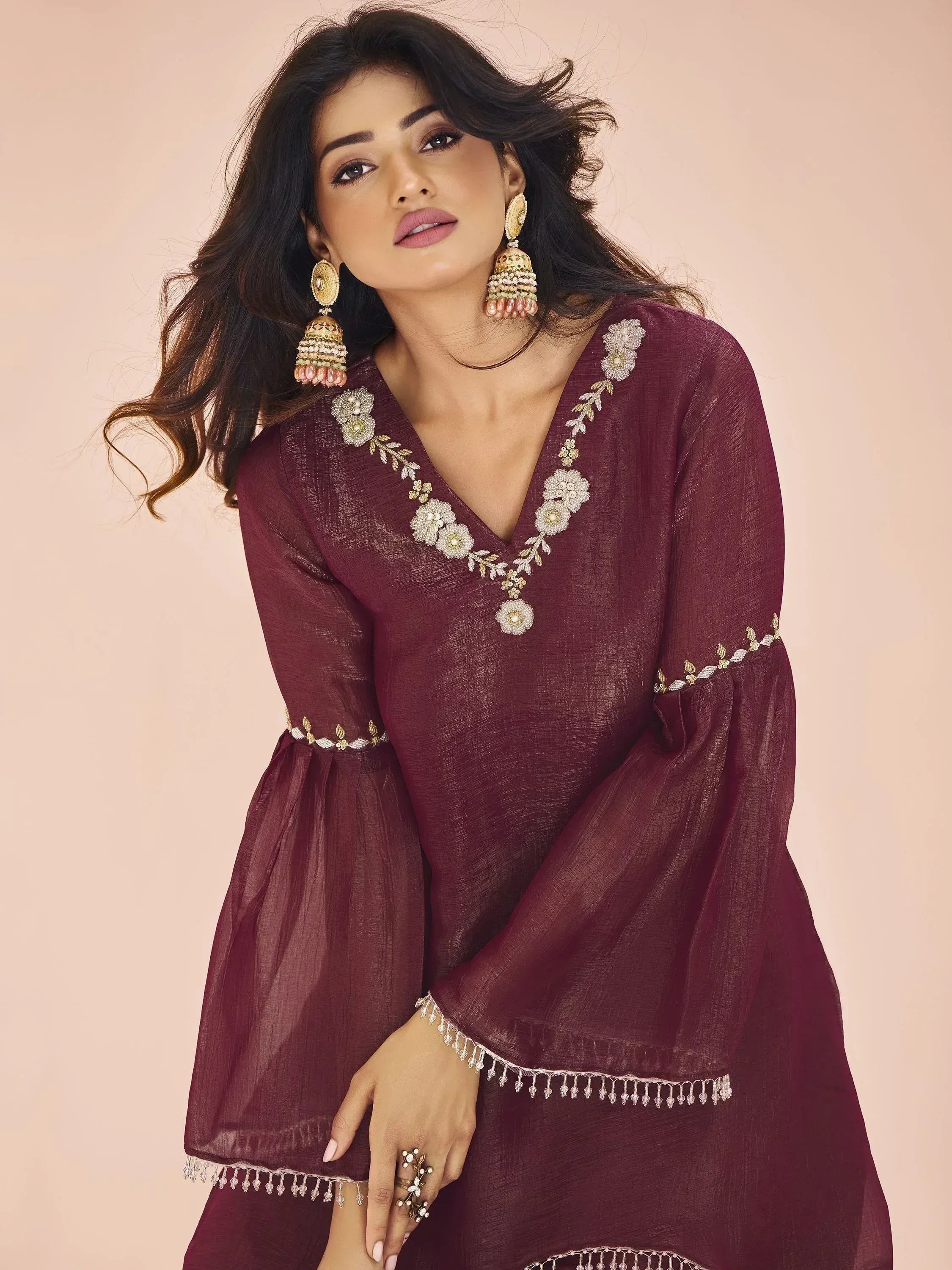 Maroon ethnic kurta with floral embroidery and bell sleeves, paired with jhumka earrings