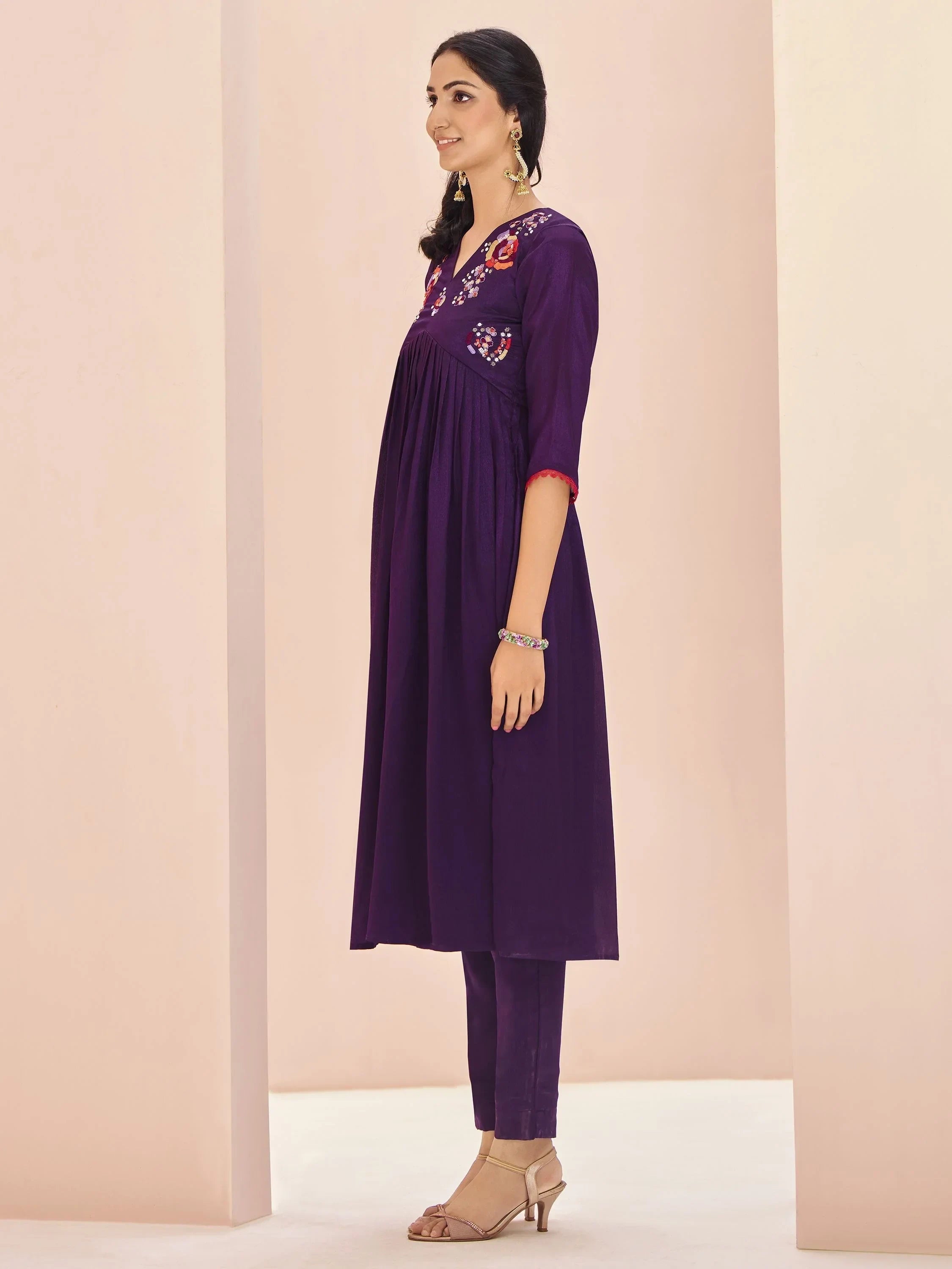 Woman in purple Indian kurti with floral embroidery and churidar pants, side pose