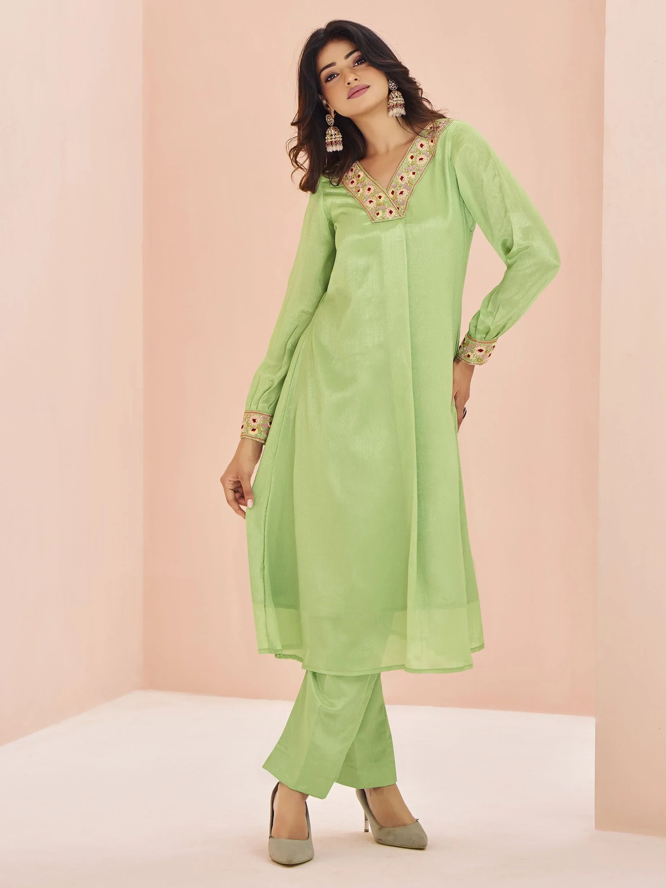 Woman wearing light green ethnic salwar kameez with embroidered neckline and cuffs