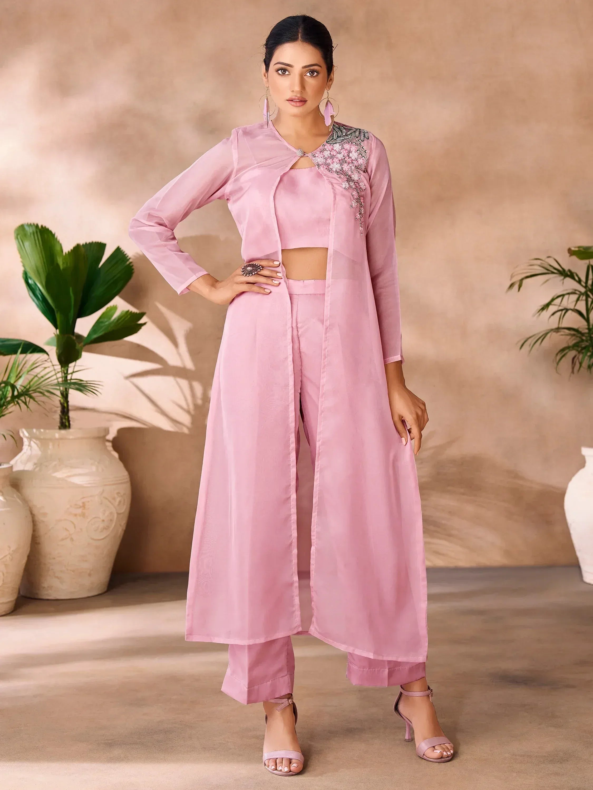 Woman in pastel pink embroidered ethnic gown with long jacket and pants, indoor setting
