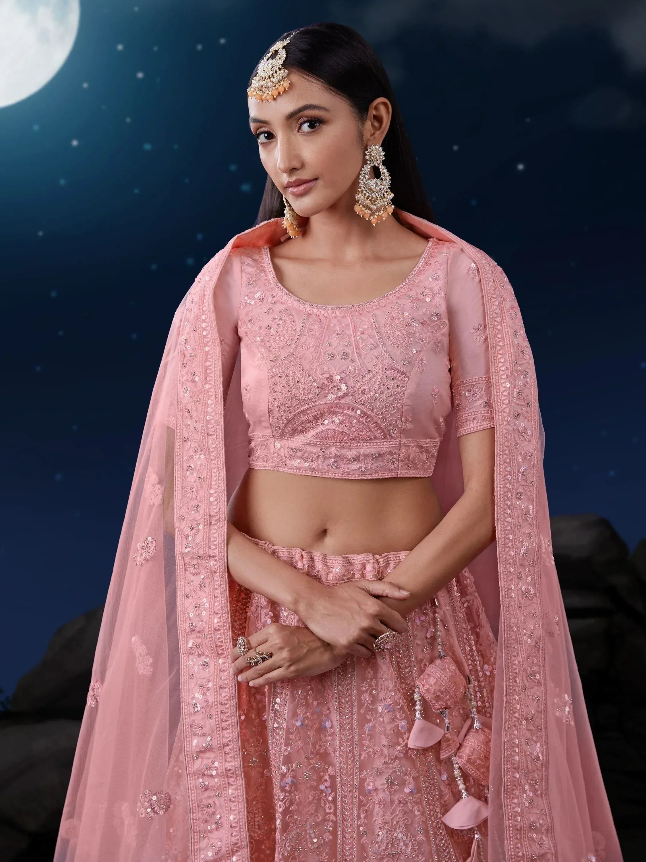 Pink embroidered lehenga choli with dupatta, perfect for Indian weddings and festive occasions under moonlight.