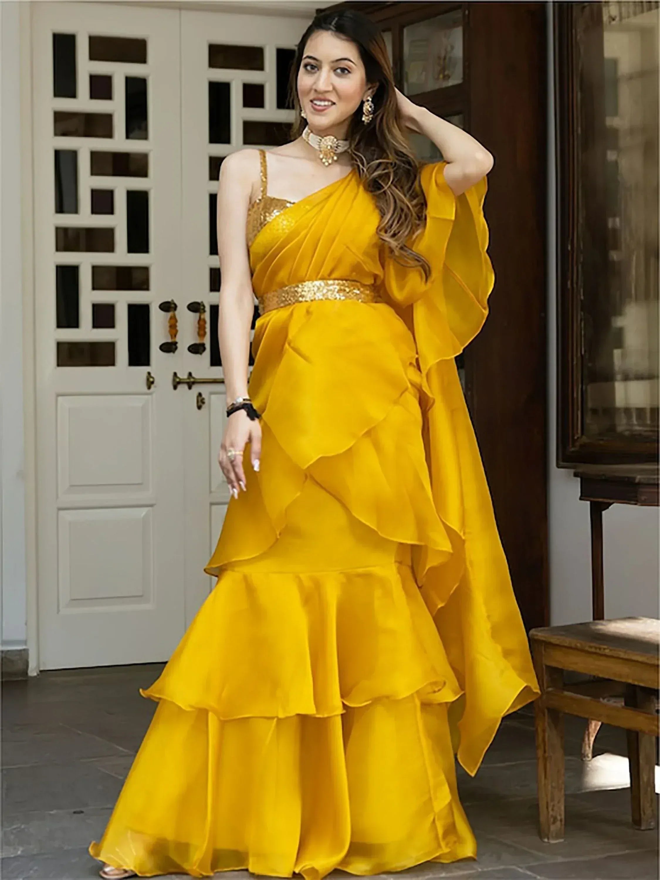 Yellow ethnic gown with ruffled layers, gold belt, and one-shoulder design for festive occasions