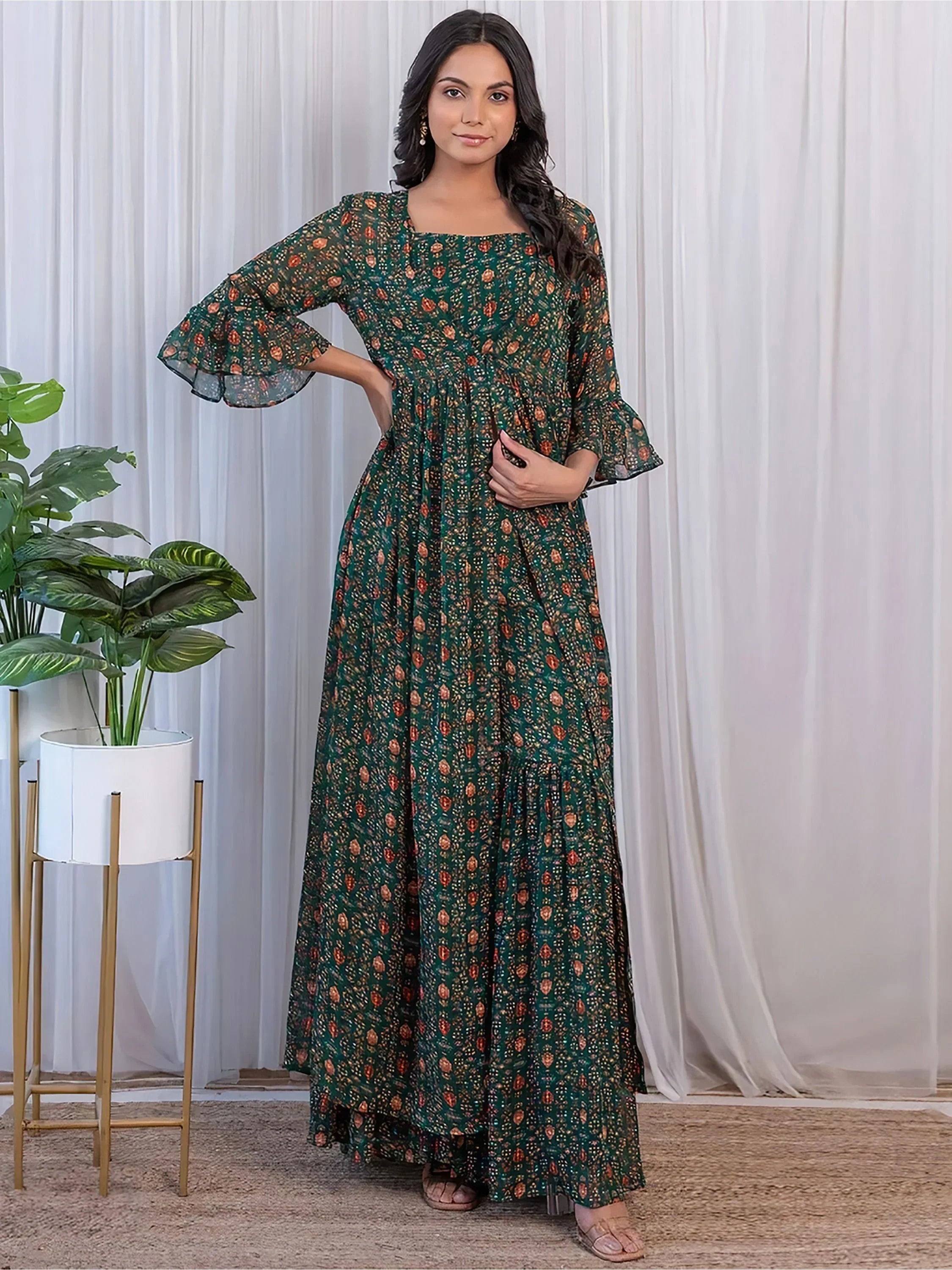 Woman wearing a green printed ethnic gown with flared sleeves, standing indoors