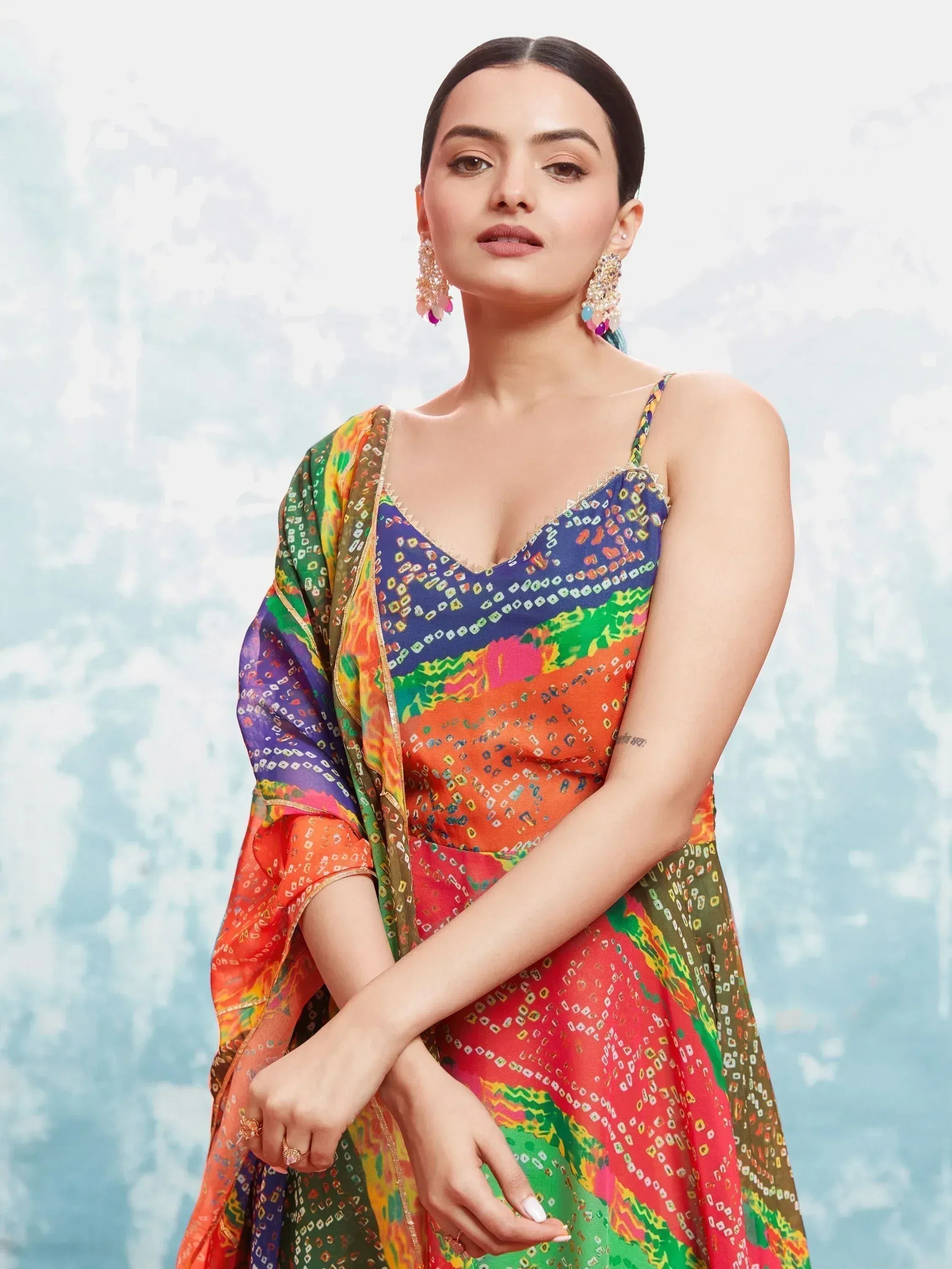 Woman wearing colorful bandhani print lehenga choli with dupatta and statement earrings