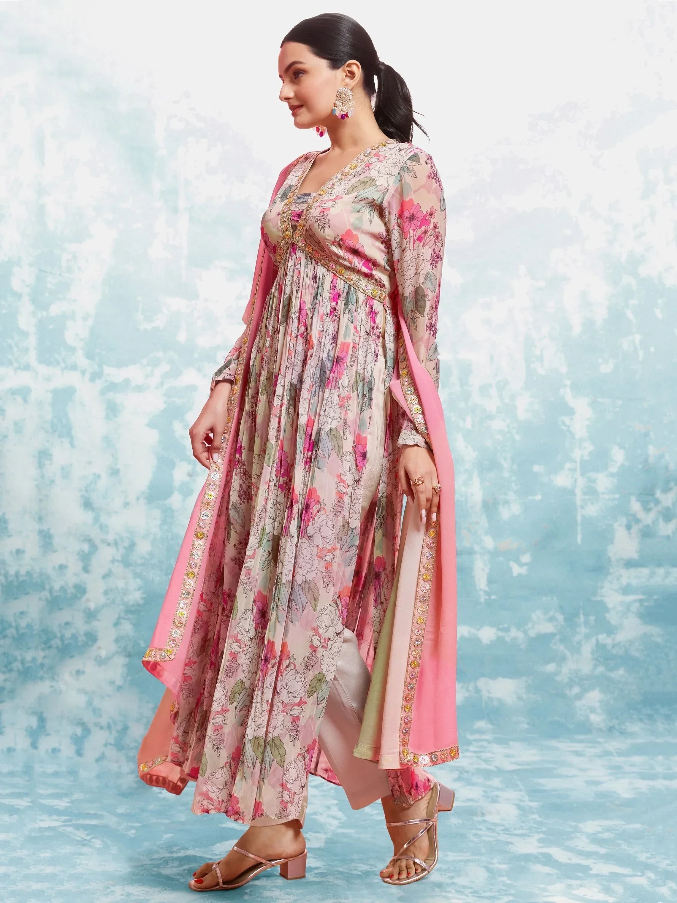 Woman in floral print Anarkali suit with pink dupatta and ethnic jewelry, stylish Indian outfit