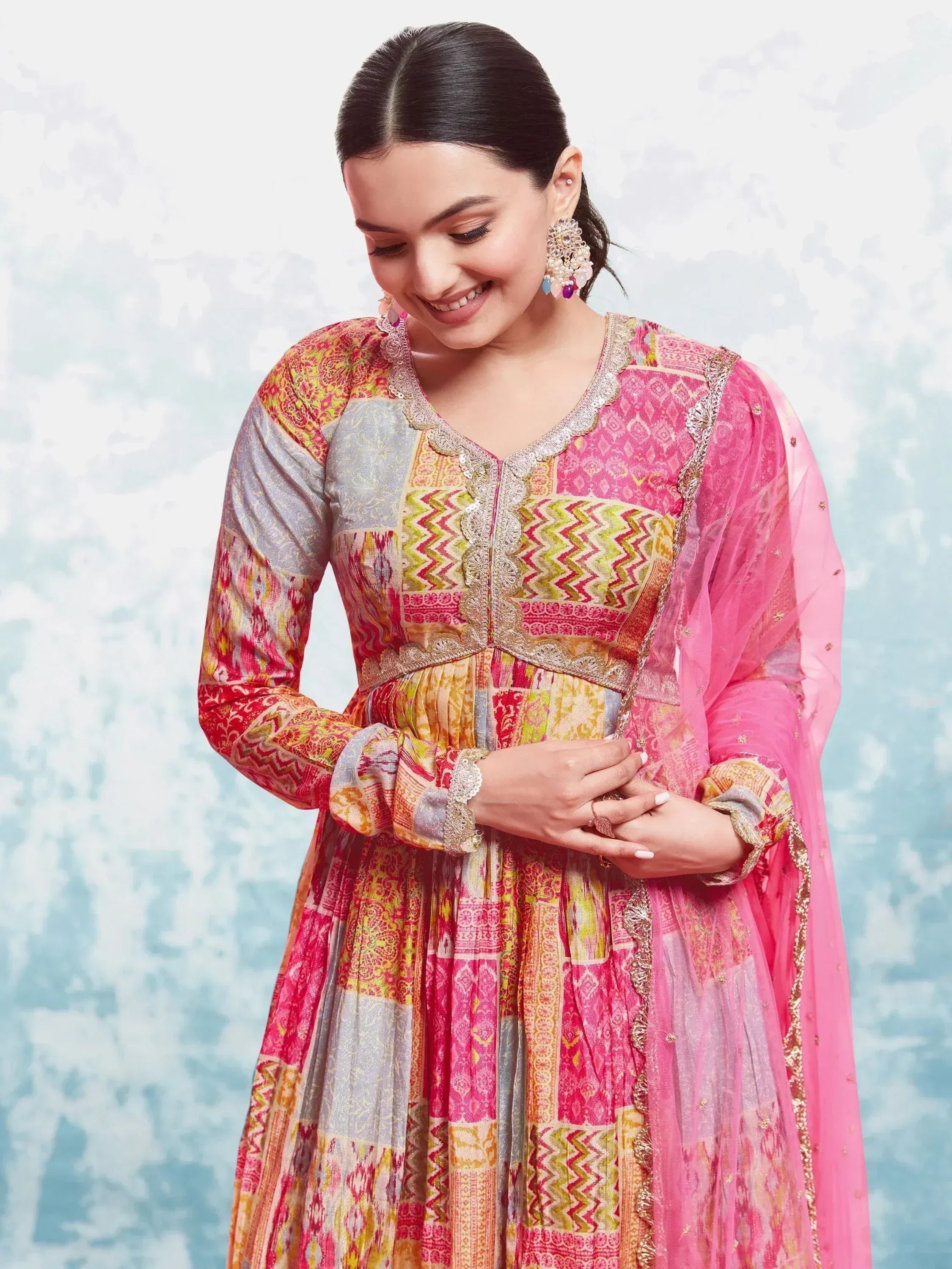 Woman in vibrant multicolor printed Anarkali gown with pink dupatta and statement earrings