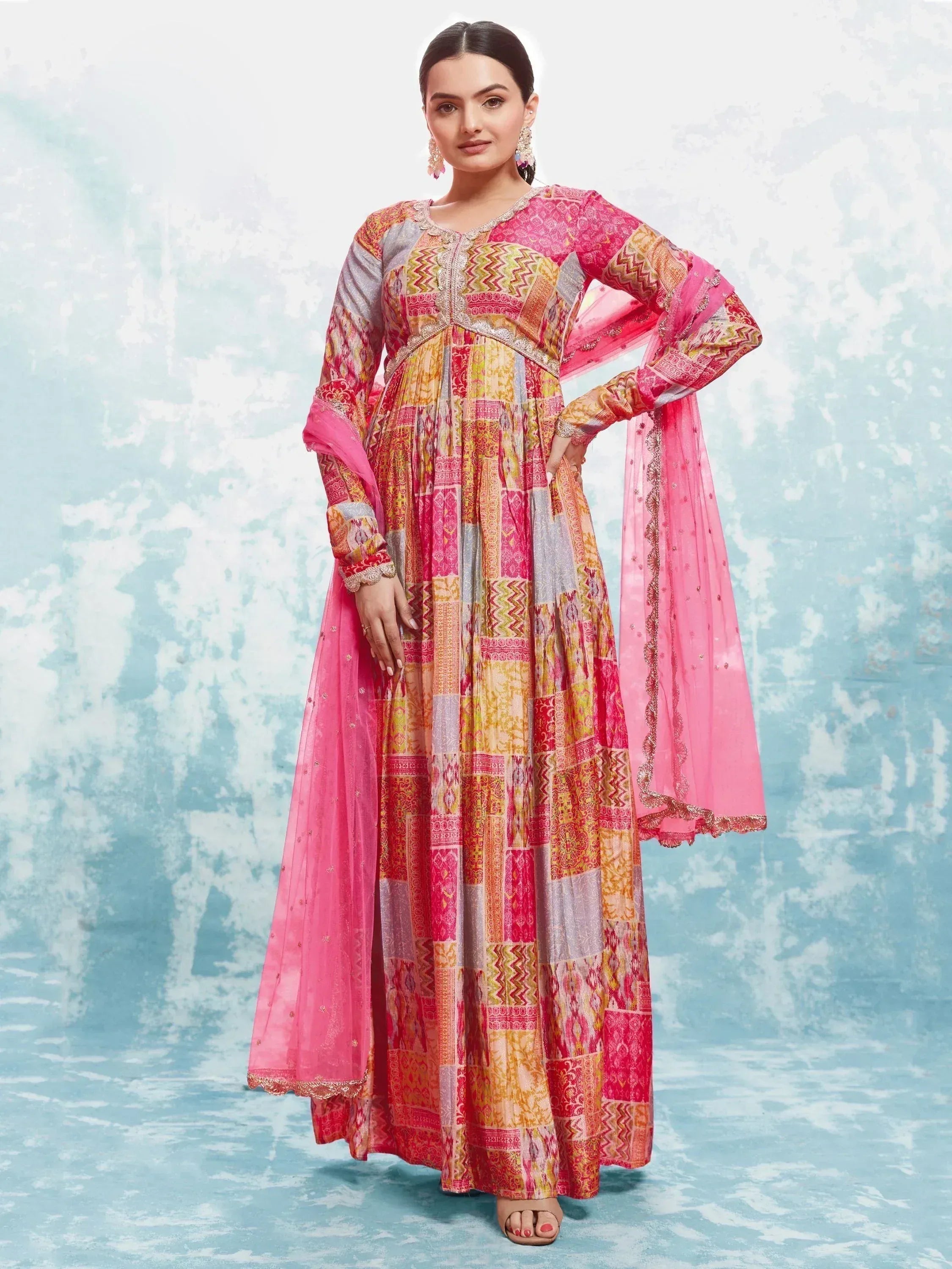Woman wearing a colorful patchwork Anarkali suit with long sleeves and pink dupatta